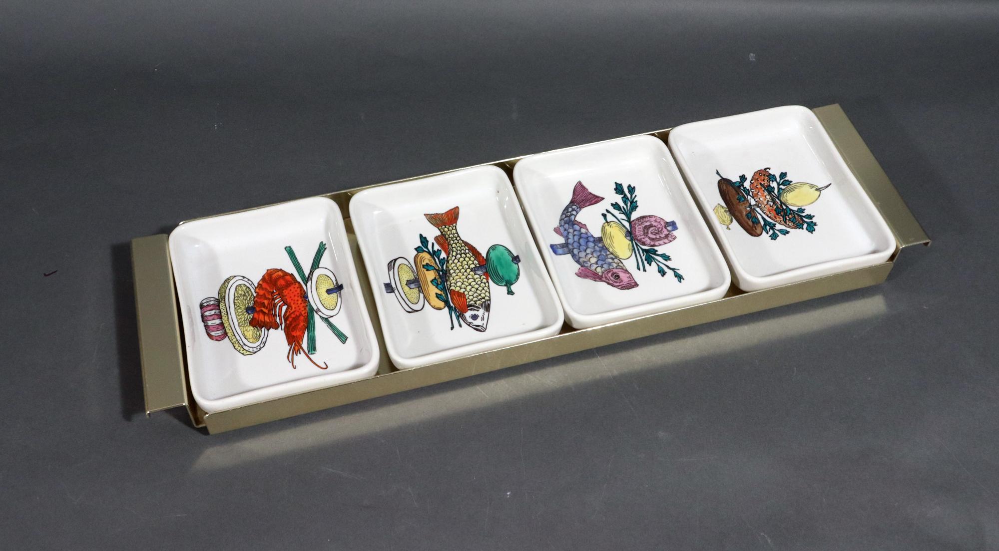 Piero Fornasetti Ceramic Appetizer Fish Kebab Dishes and Serving Tray,
1960s

There are four ceramic deep rectangular dishes placed in a long rectangular gold metal tray with handles at each end.
The trays together display a single large fish kebab