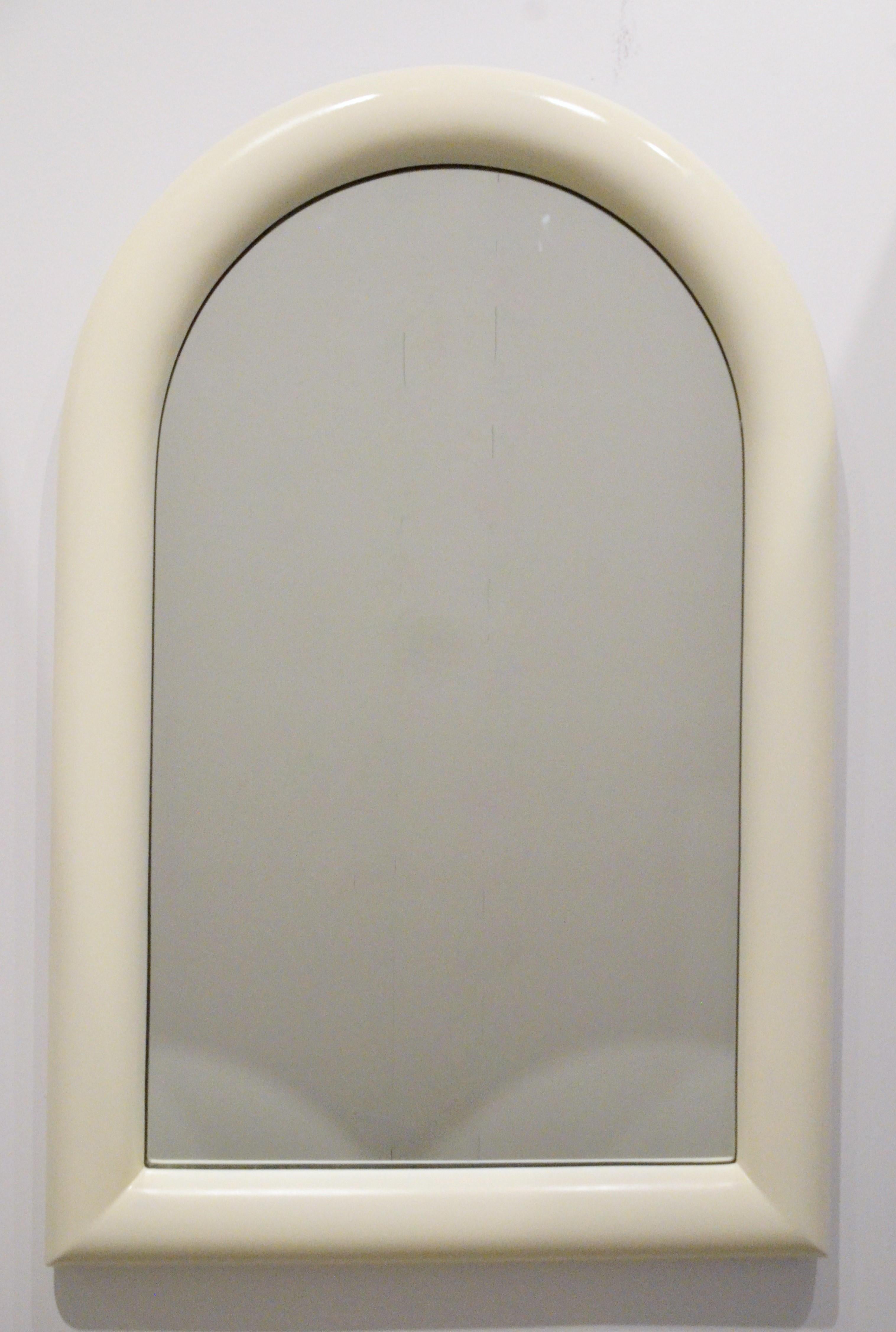 Offered is a Mid-Century Modern Pierre Cardin attributed arched topped wall mirror newly lacquered in a creamy white wood frame. Pierre Cardin's signature style of futuristic forms combined with traditional finishes are echoed in this piece. This