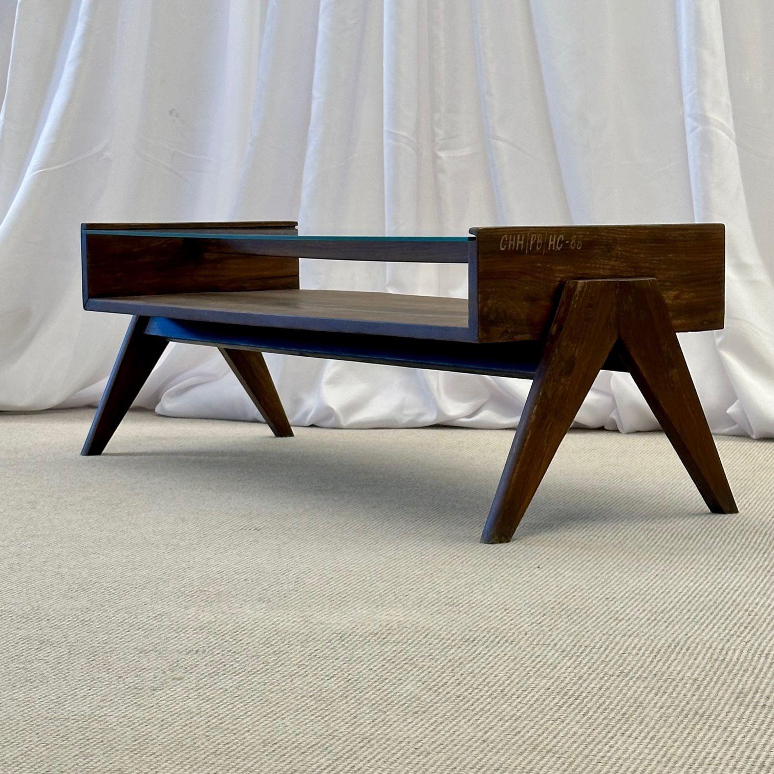 Pierre Jeanneret Rectangular Glass Coffee Table, Model PJ-TB-05-A
 
This collector's coffee table features the signature compass V-leg base, open cabinet concept center shelf, glass top and tapered legs.
 
France, India, c. 1960s
Teak, Glass
 
With