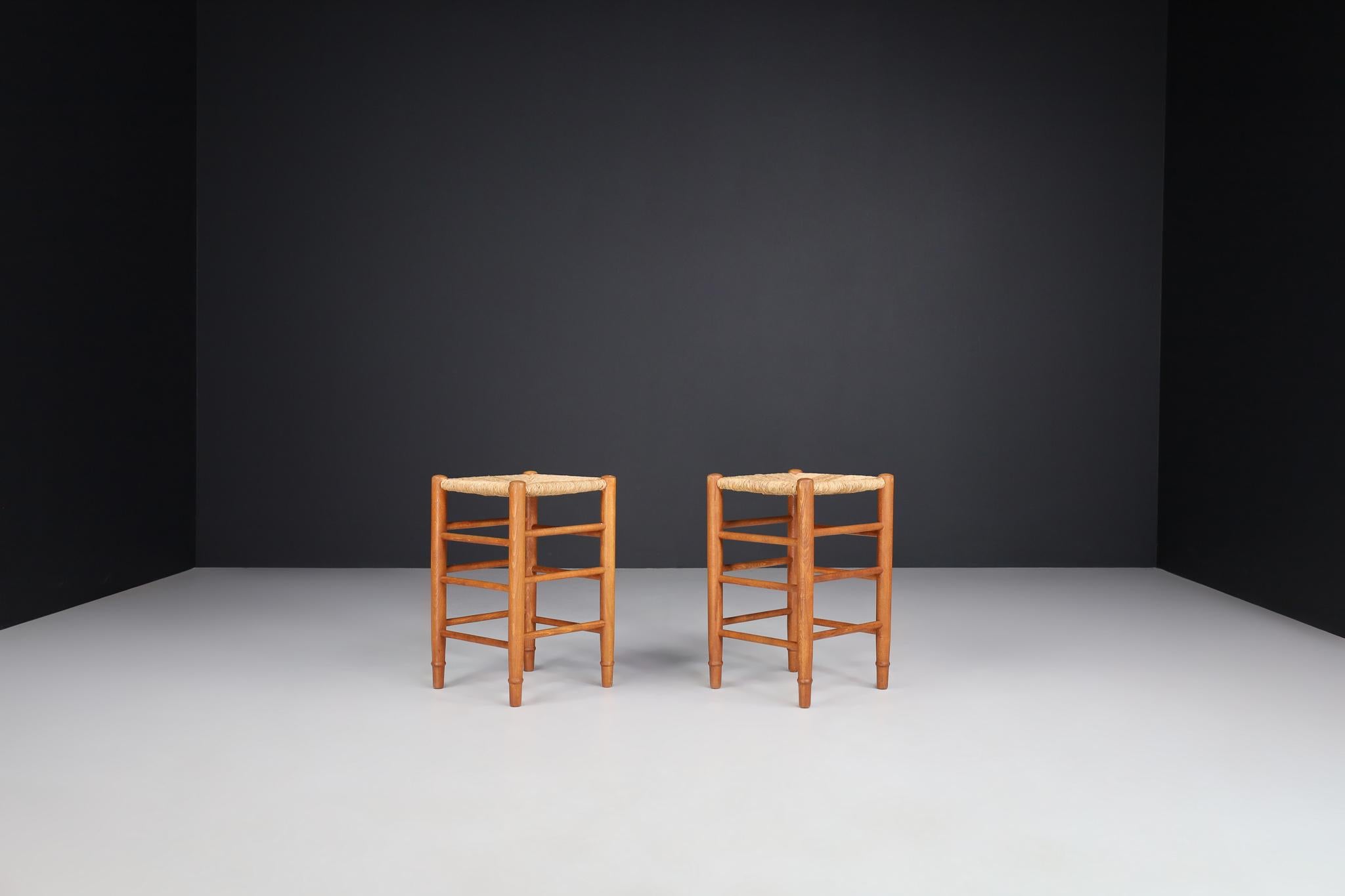 Pair of two French stools in the style of Charlotte Perriand, France, 1950s.

These solid oak stools show a lovely natural patina, are in excellent original condition and have a great patina and natural wear to the wood and rush. These stools would