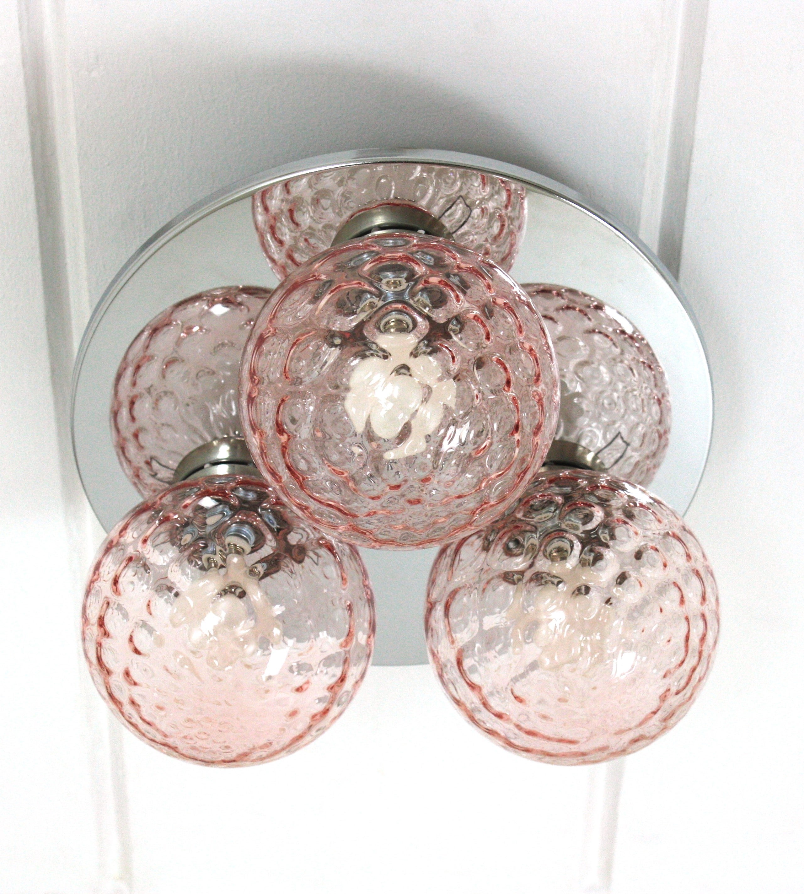 Italian Spherical Textured Globe Glass Flush Mount Ceiling Light Fixture with Chrome Base, 1960s.
This eye-catching ceiling light features a chromed steel round backplate holding 3 venetian pink blown glass globes with textured details.
The pinkish