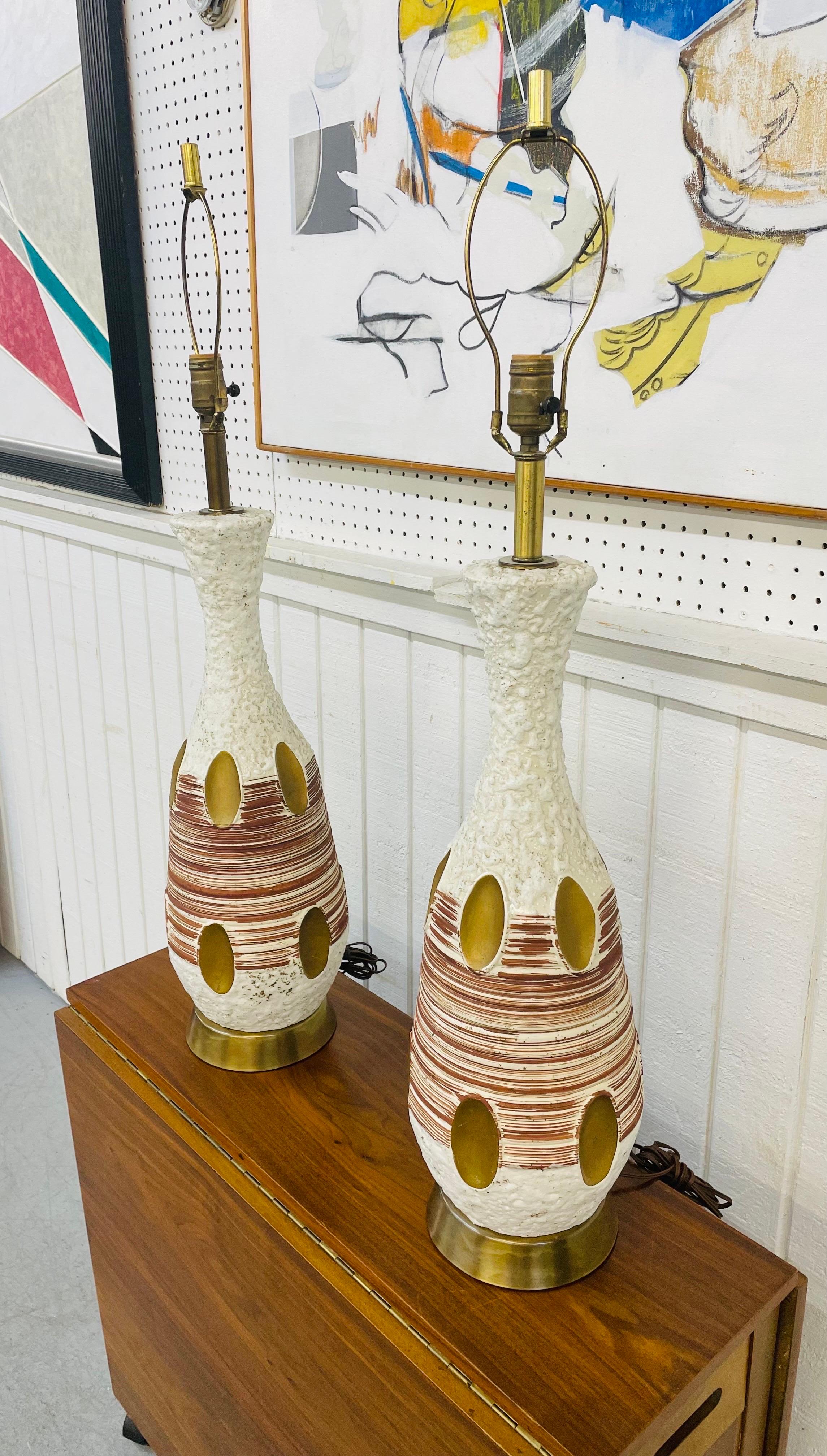 This listing is for a pair of Mid-Century Modern Plaster Table Lamps. Featuring a brass base, brass oval accents, paint decorated design, and original cord.