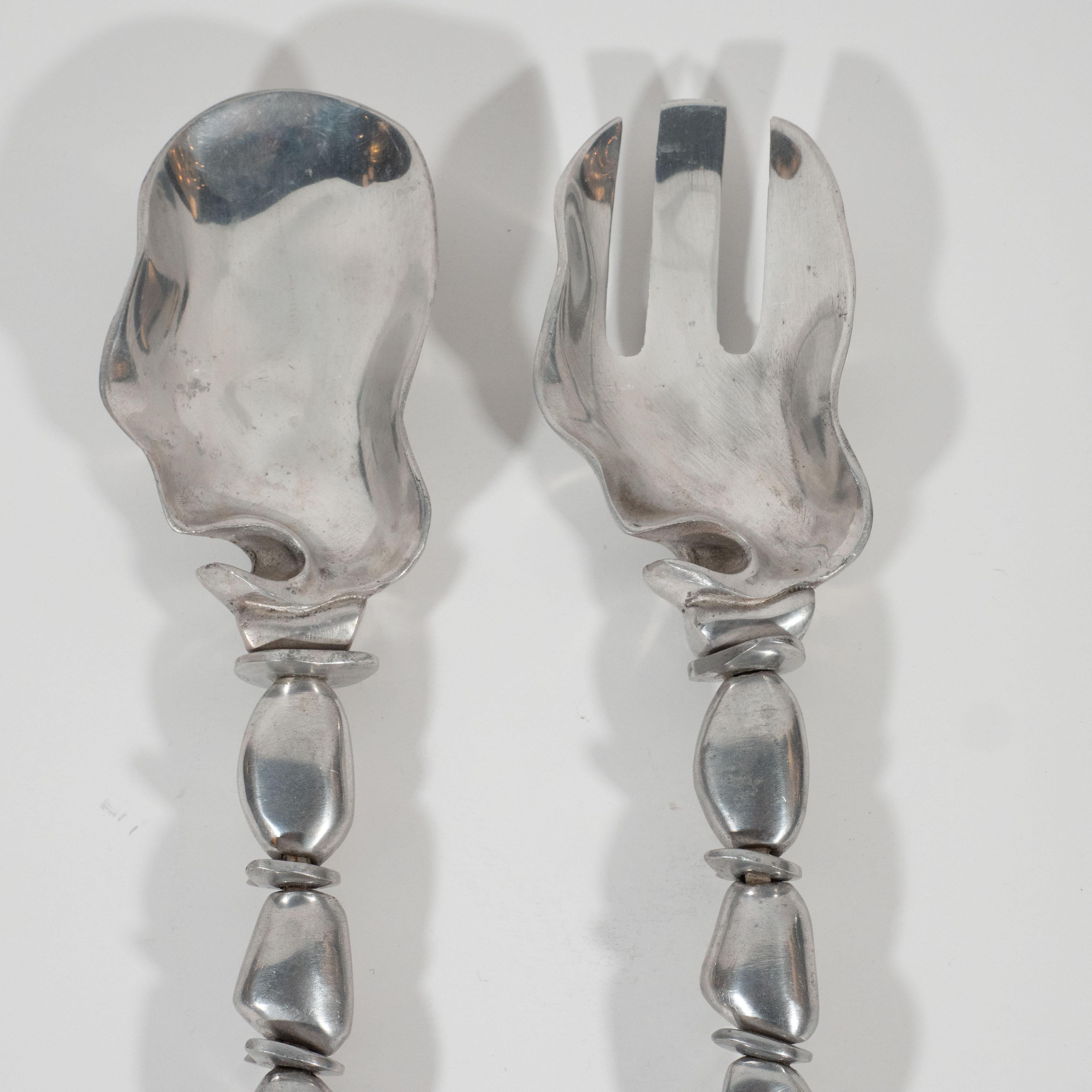 This sophisticated serving set or salad tongs were realized by the esteemed Mid-Century Modern designer Arthur Court, circa 1970. They feature bowls resembling abstracted oyster shells while their handles- consisting of an array of organically