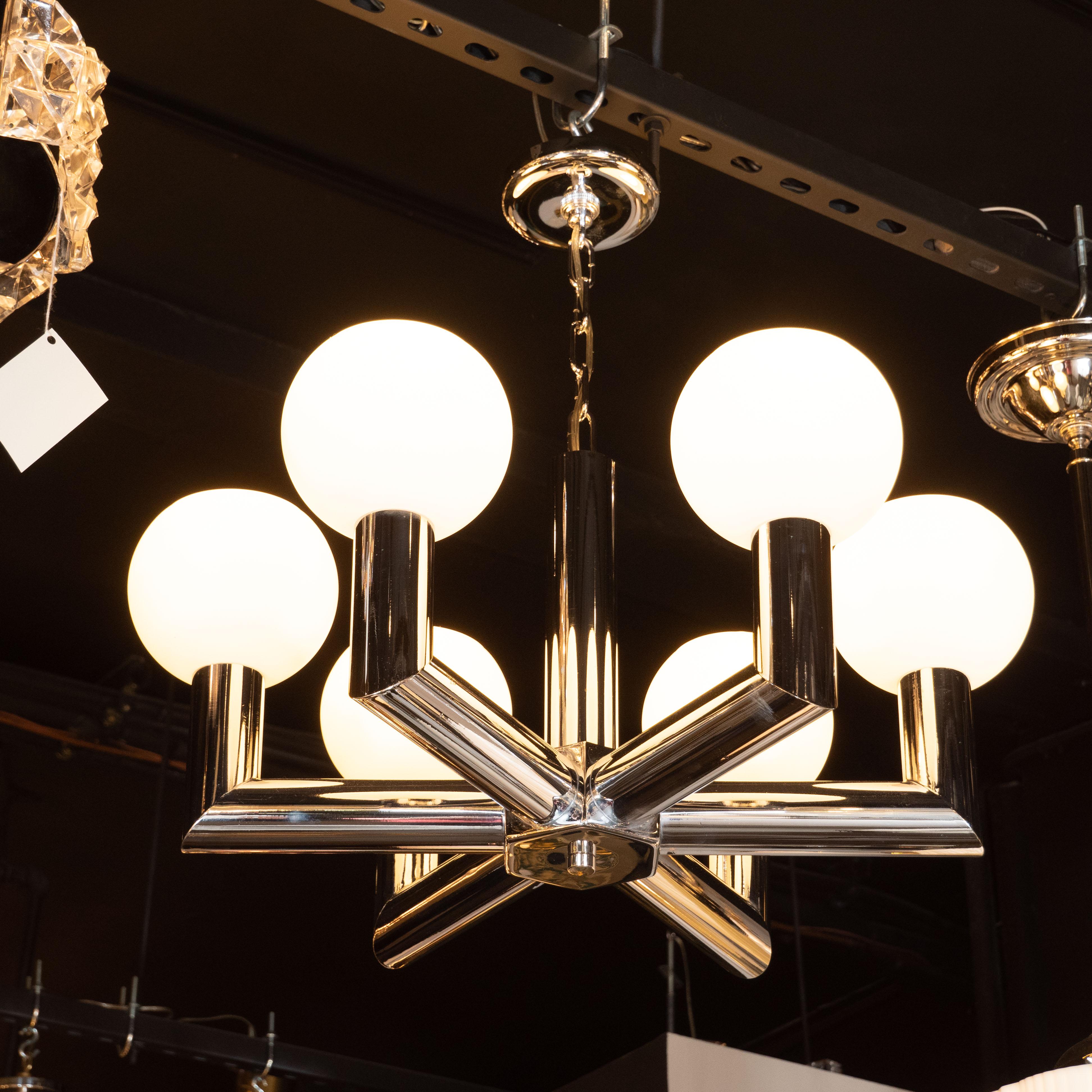 This refined Mid-Century Modern chandelier was realized by the esteemed Italian maker, Sciolari, in Italy, circa 1970. It features six cylindrical arms that extend outwards from a central hexagonal body before ascending upwards at right angles. The