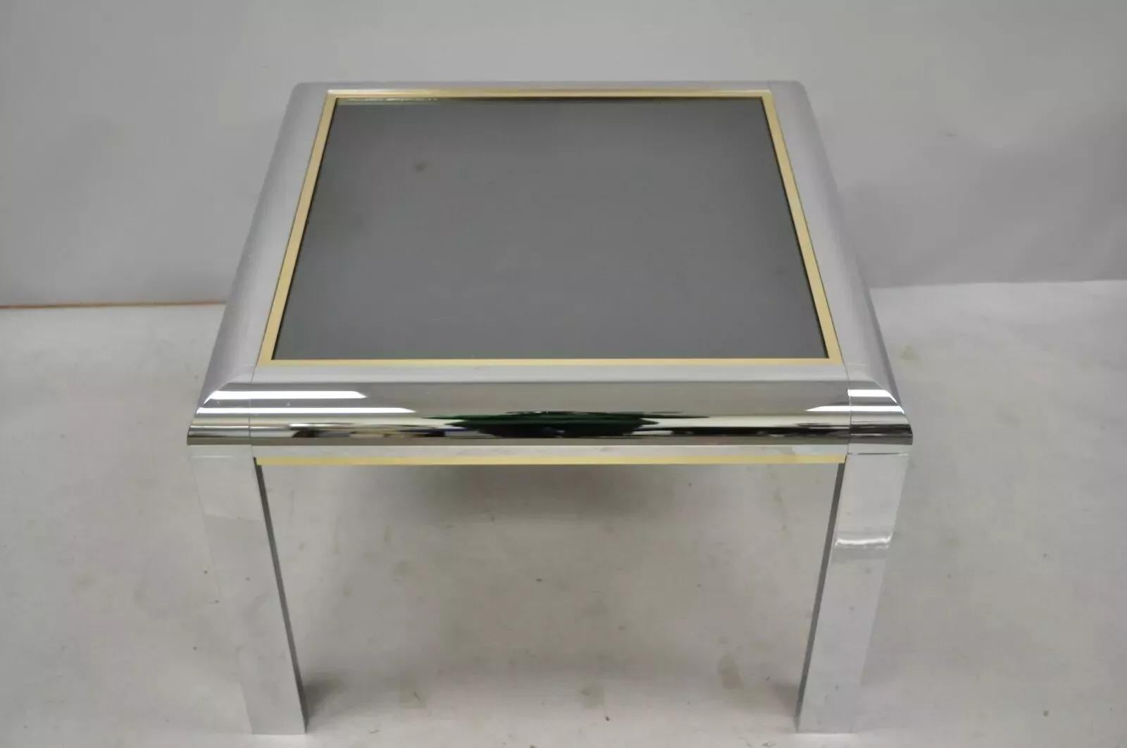 Table d'appoint à plateau en verre de style Milo Baughman en chrome poli. L'article se caractérise par un plateau en verre miroir fumé, un cadre en chrome poli, des garnitures en laiton, des lignes modernistes épurées, un style et une forme