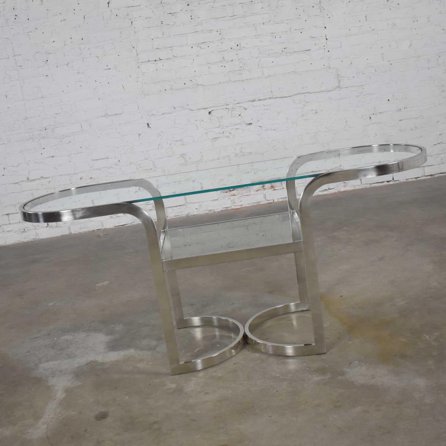 Fabulous Mid-Century Modern polished chrome sofa or console table, lower shelf with glass insert, and oval glass top. Gorgeous condition with wear consistent with age as expected with vintage pieces. Please see photos. Circa 1970-1980.

You know