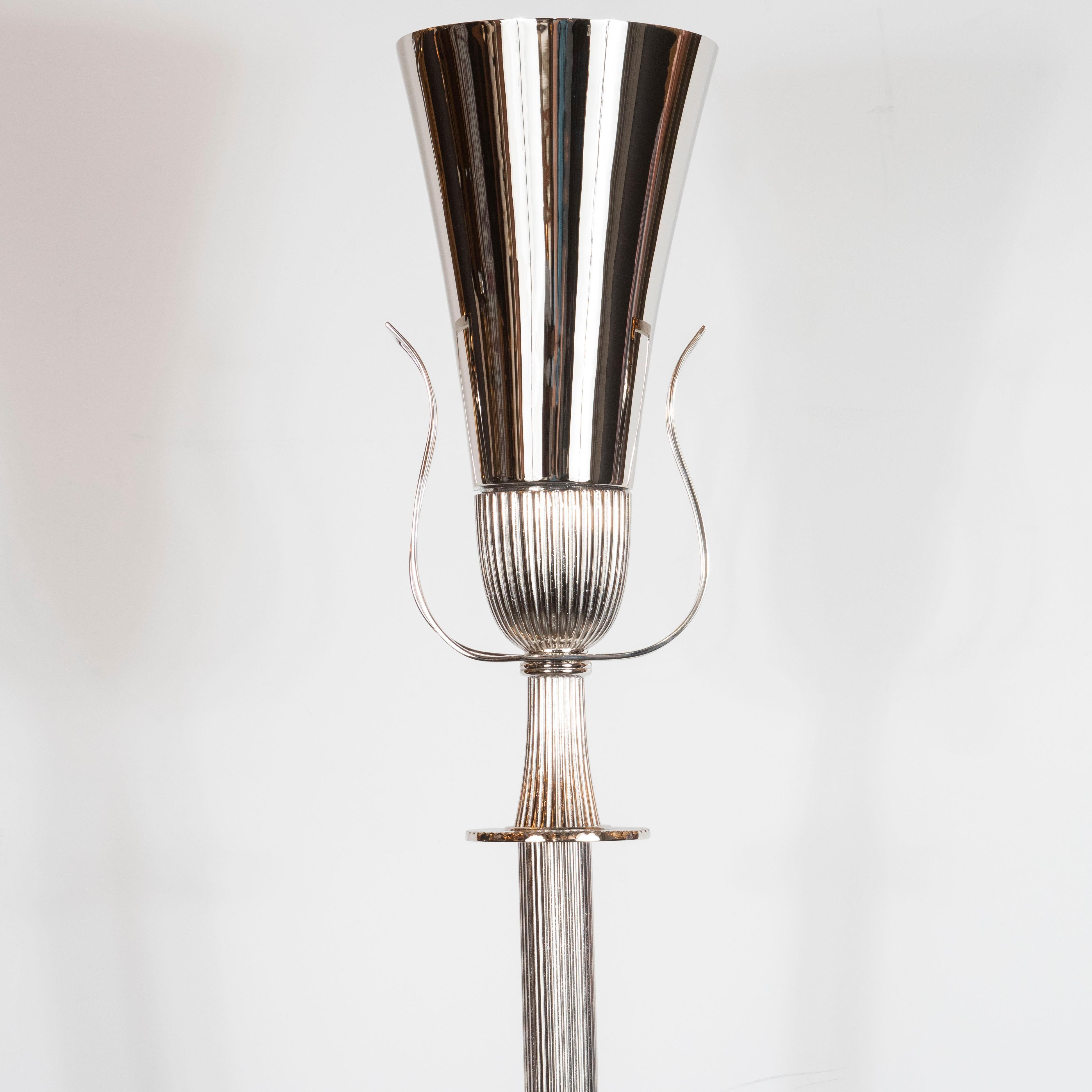 This elegant Mid-Century Modern torchère was realized by the fabled 20th century design luminary Tommi Parzinger in the United States, circa 1950. It features a reeded body that attaches to an hourglass form neck with undulating open form