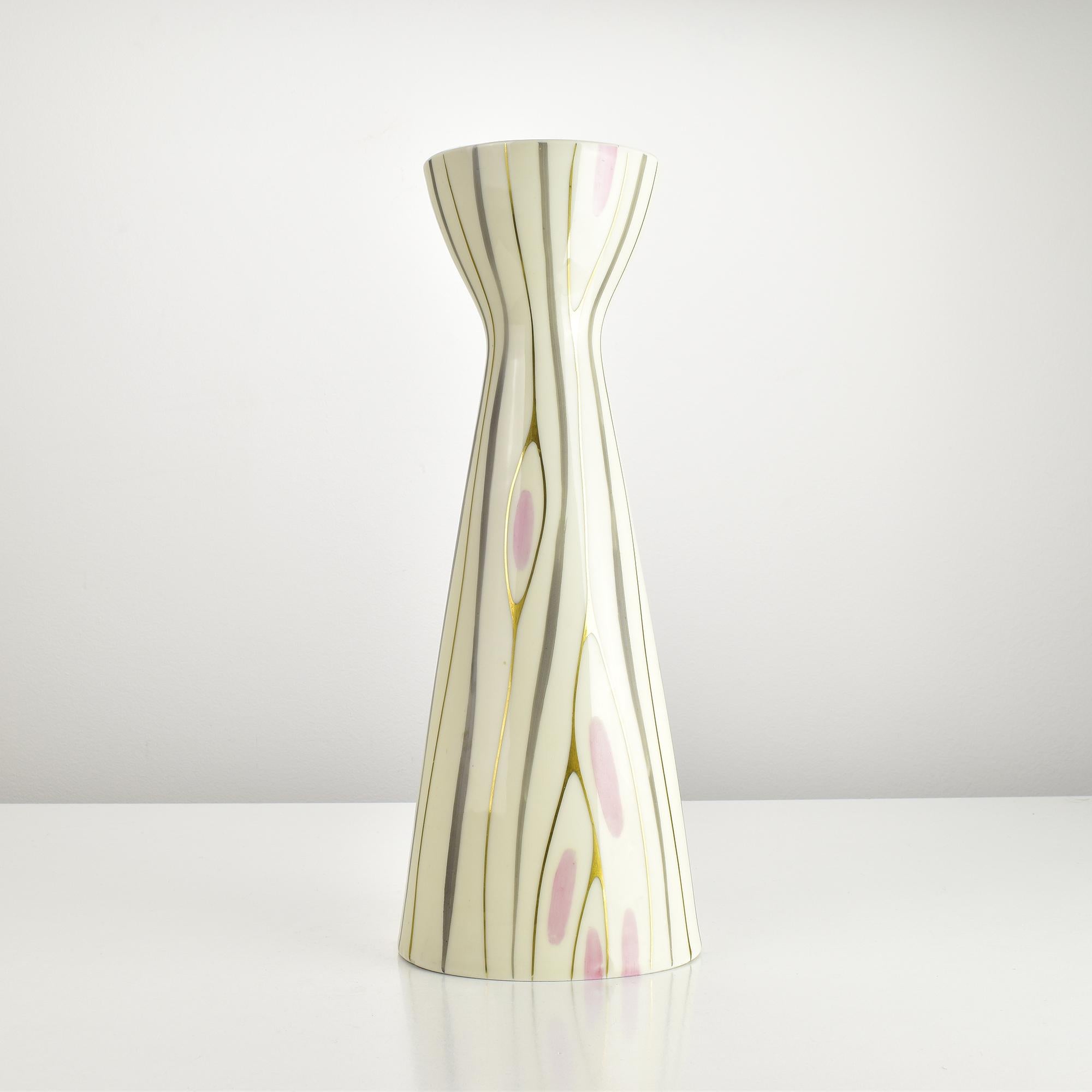 Cet étonnant vase en porcelaine du Modern-Decor présente une élégante forme de diabolo ou de sablier et est décoré d'un motif organique accrocheur dans des tons doux de rose, gris et crème accentués par des lignes dorées peintes à la main. Le design