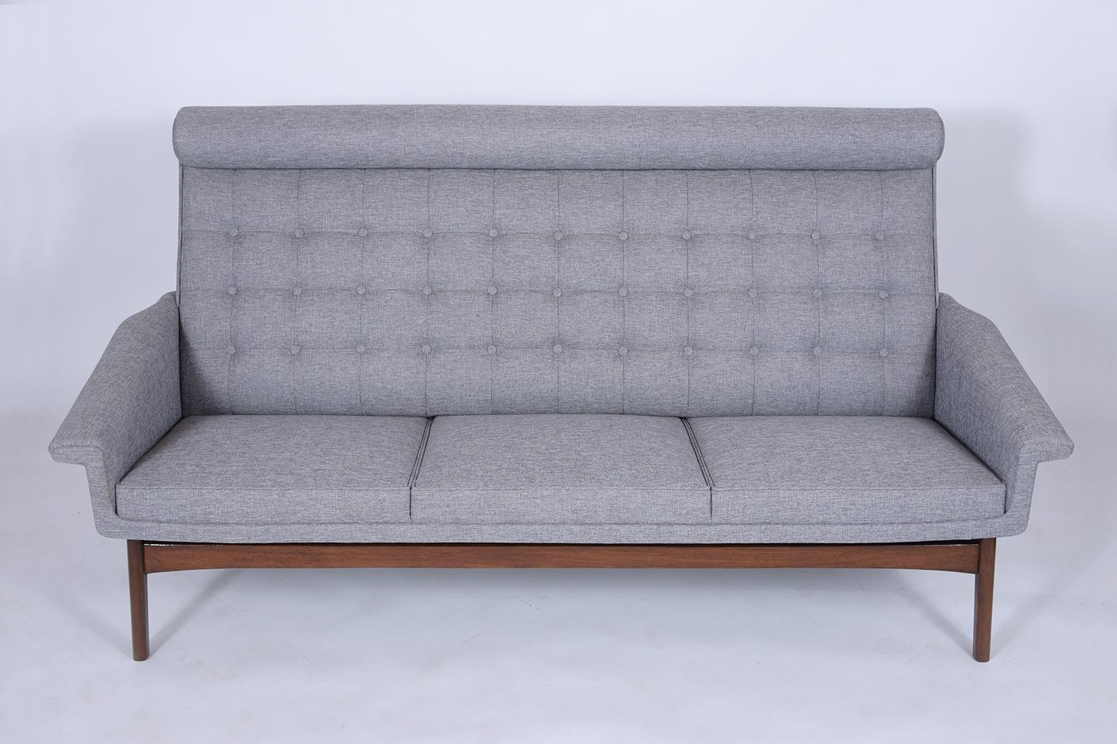 An extraordinary 1960s Danish Poul Jensen sofa is made with a solid teak wood frame that has been finished in a walnut color with patina finish and is newly restored. The simplicity of the frame is accented by the new professionally upholstered