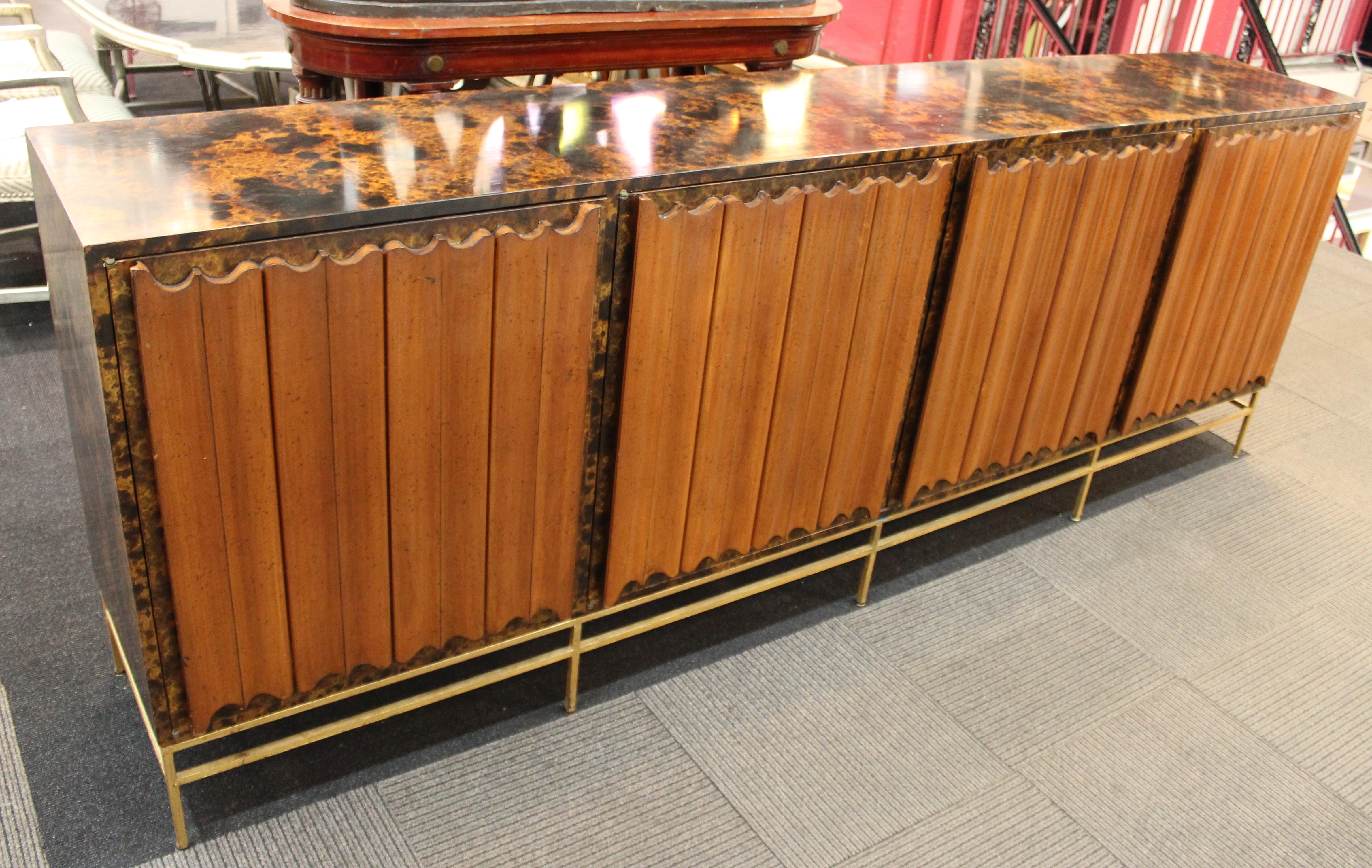 Monumental American Mid-Century Modern credenza or sideboard in the style of Harvey Probber, with tortoiseshell finish and four linen-fold style front panel doors atop a gilt metal frame. The piece dates from the mid-20th century and is in great