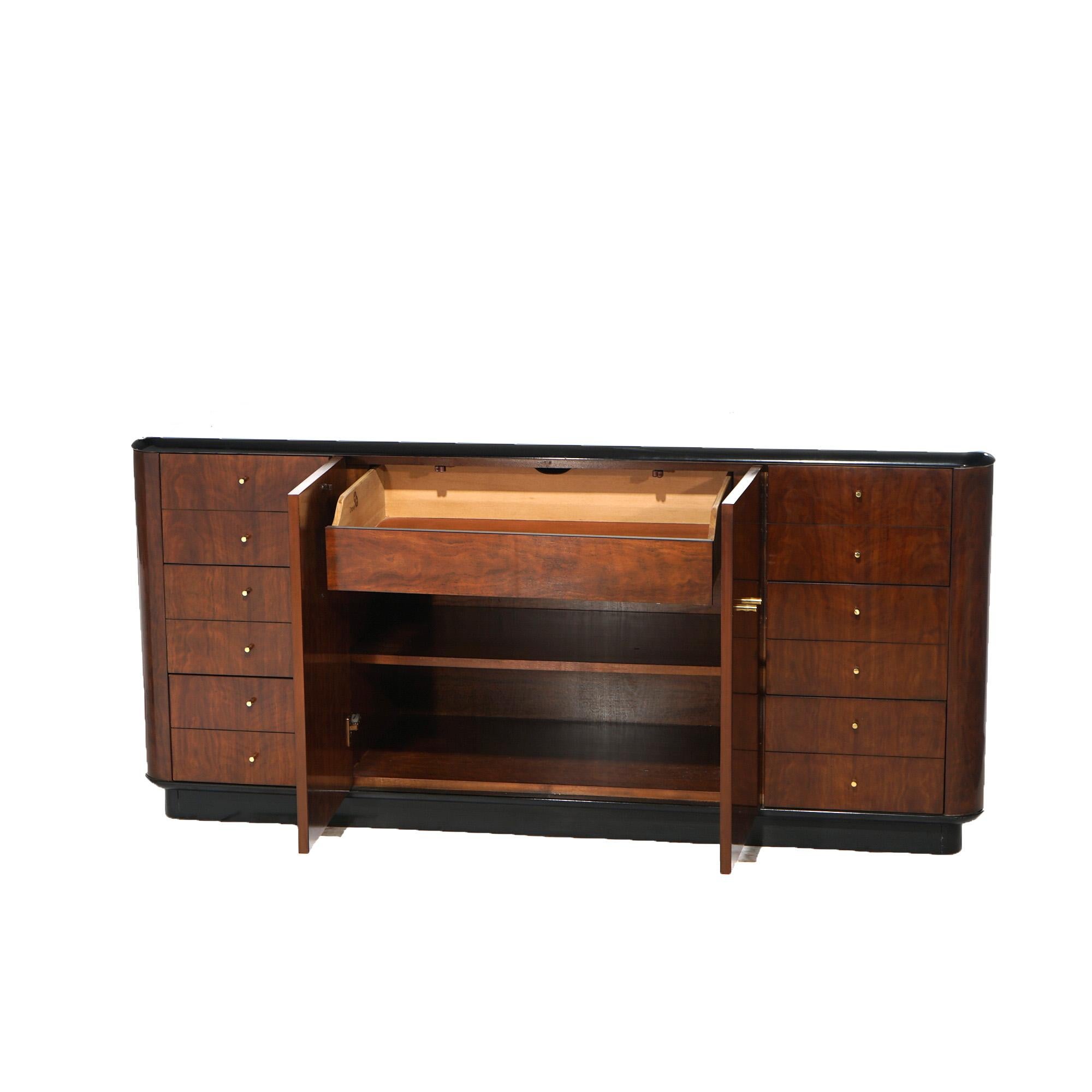A Mid Century Modern sideboard dresser by Drexel in the Profiles line offers mahogany construction with ebonized top over case with central double door cabinet and having flanking drawer towers, raised on an ebonized base, maker mark as