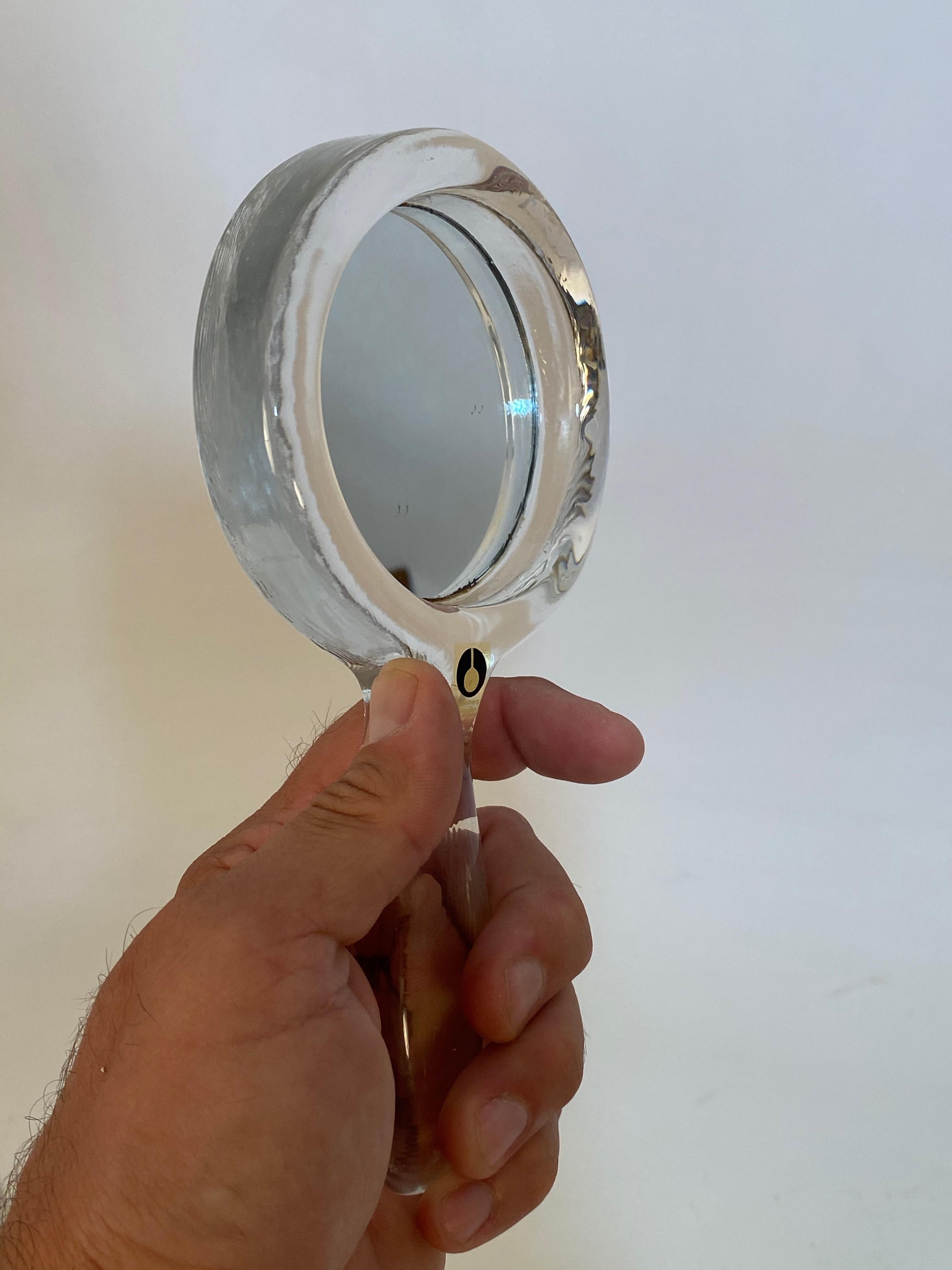 Signed clear molded glass hand mirror. Pukeberg, Sweden, circa 1960-1970. Very good condition with no cracks, chips or scratches to mirrored glass.

Measures: Approximately 4