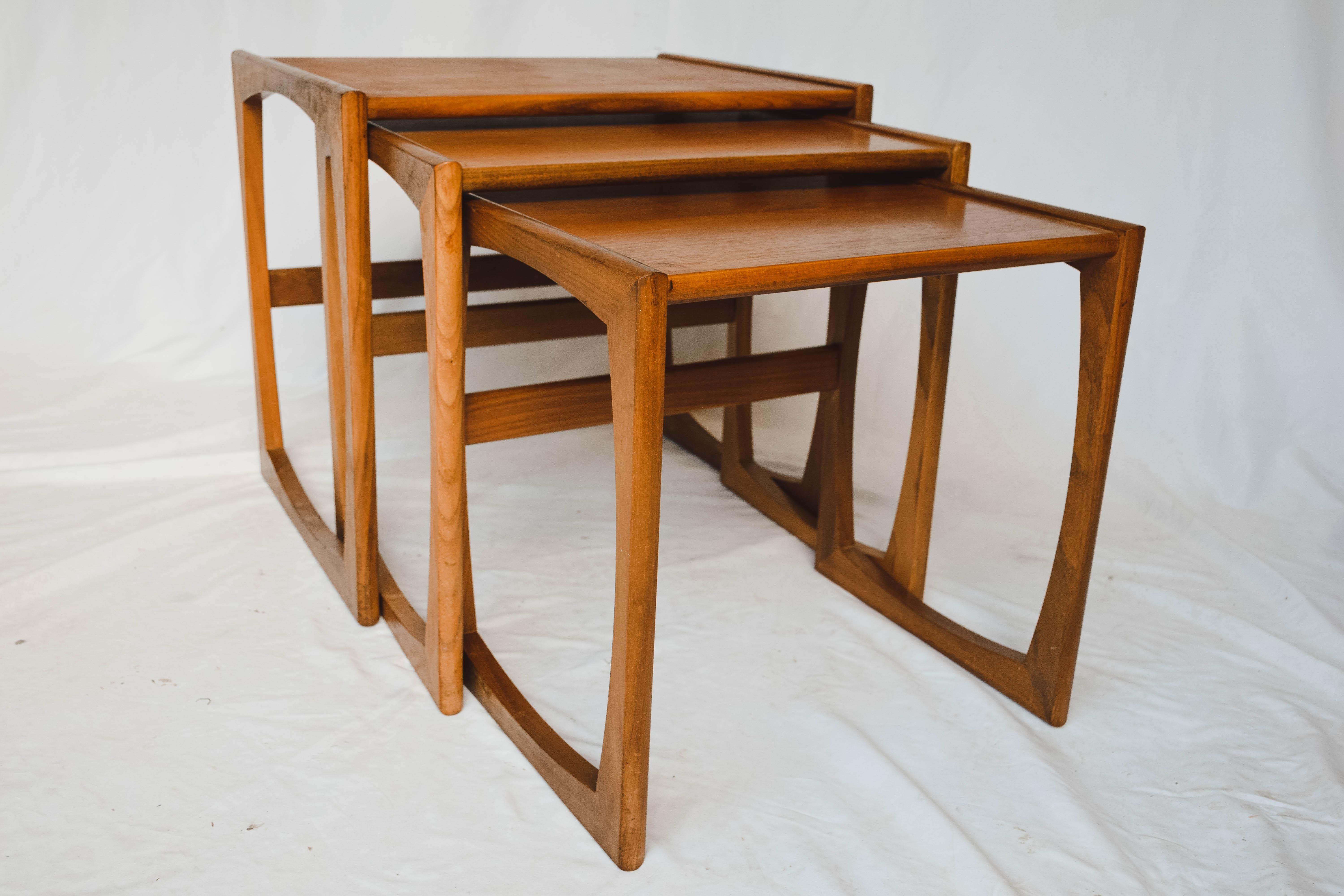 This beautiful set of three nesting tables in teak designed by R. Bennett for G Plan manufactured in England in the 1960s. These G-Plan teak Mid-Century Modern nesting tables with rounded edge 'sleigh' legs are the Quadrille model. This style has