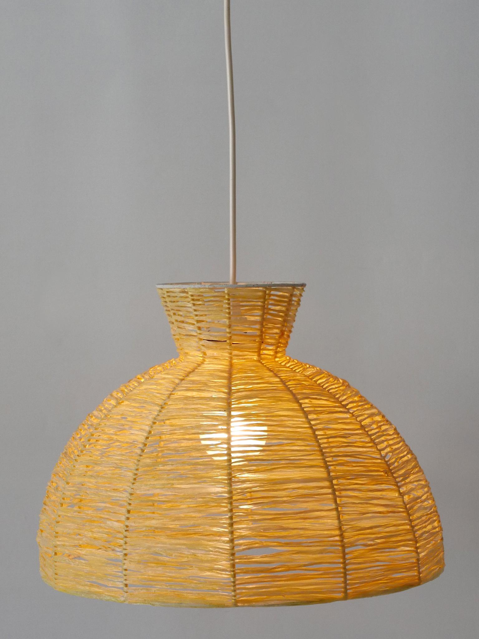 Rare, elegant and highly decorative Mid-Century Modern pendant lamp / hanging light. Manufactured in Germany, 1970s.

Executed in raffia bast and metal, the pendant lamp comes with 1 x E27 / E26 Edison screw fit bulb holder, is wired and in