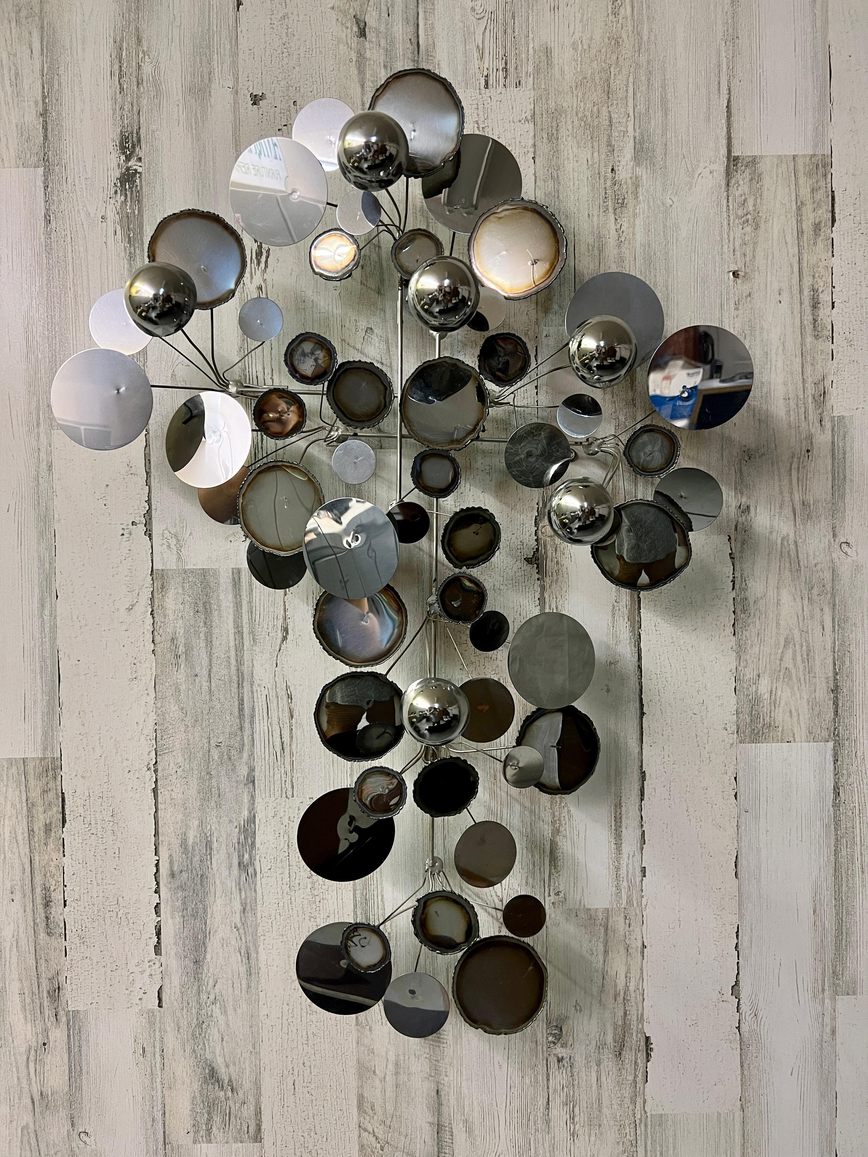 Half spheres and numerous variation of chrome with matte metal circular disc decorations mounted on a wire frame.