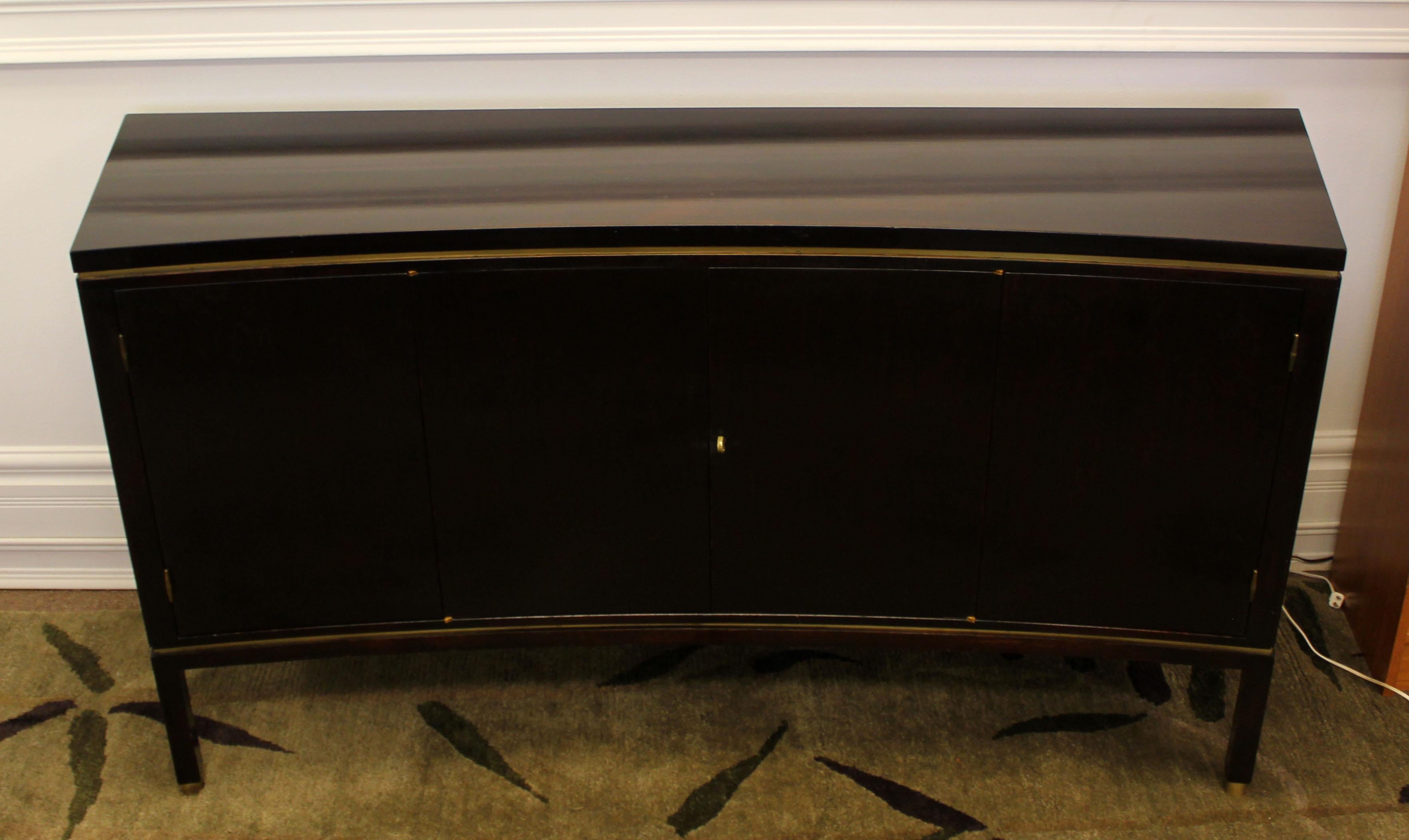 For your consideration is a rare and fantastic, curved front credenza, made of mahogany wood with brass accents, with three shelves and a compartmentalized drawer for silverware, by Edward Wormley for Dunbar, circa the 1960s. In very good condition.