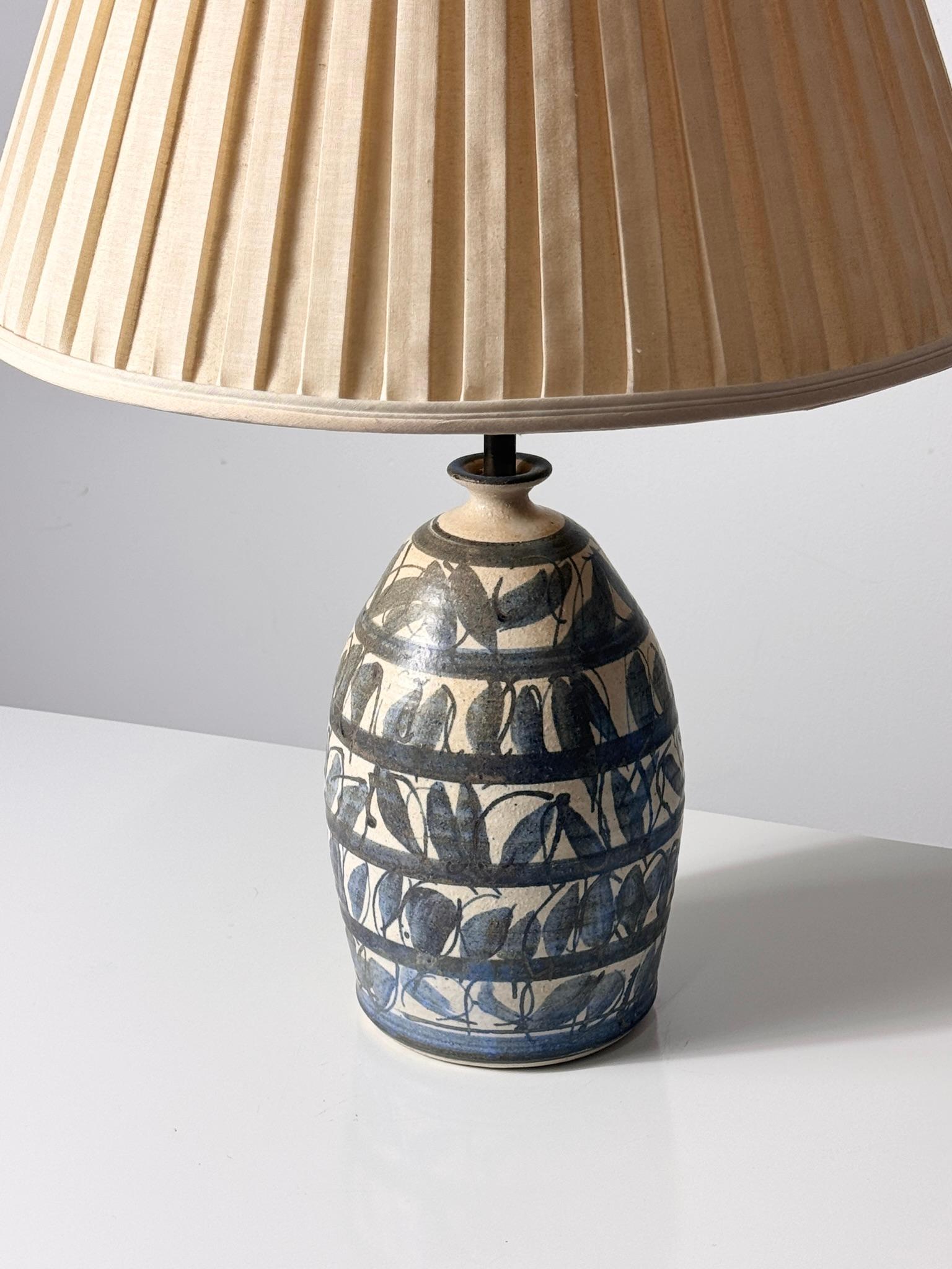 A rare table lamp by JT Abernathy of Ann Arbor MI circa 1960s
Dark blue patterned glaze with original shade

27 inch overall height
19 inch shade diameter
7 inch base diameter
12 inch base height