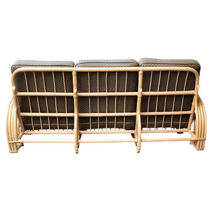 A mid-20th century rattan and bamboo 3-seat upholstered pretzel sofa in the style of Paul Frankl. Created from bent wood, rattan, and bamboo, this lovely mid-century modern couch will be a fantastic addition to any post-modern living room or patio.