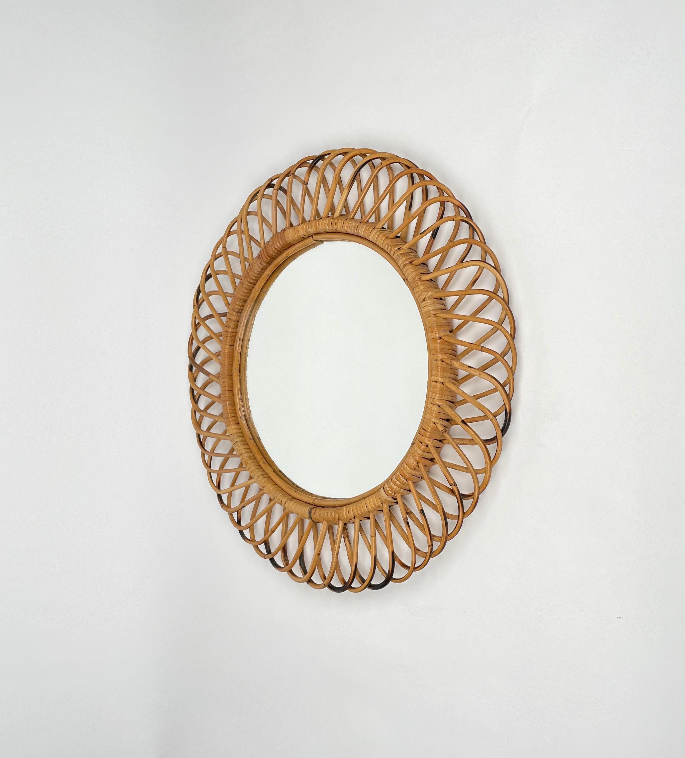 Midcentury Italian Riviera rattan and bamboo round mirror, 1960s.

This wall mirror is unique as it has a curved rattan beam and bamboo double frame, a solid internal one and an external one make of geometric patterns.