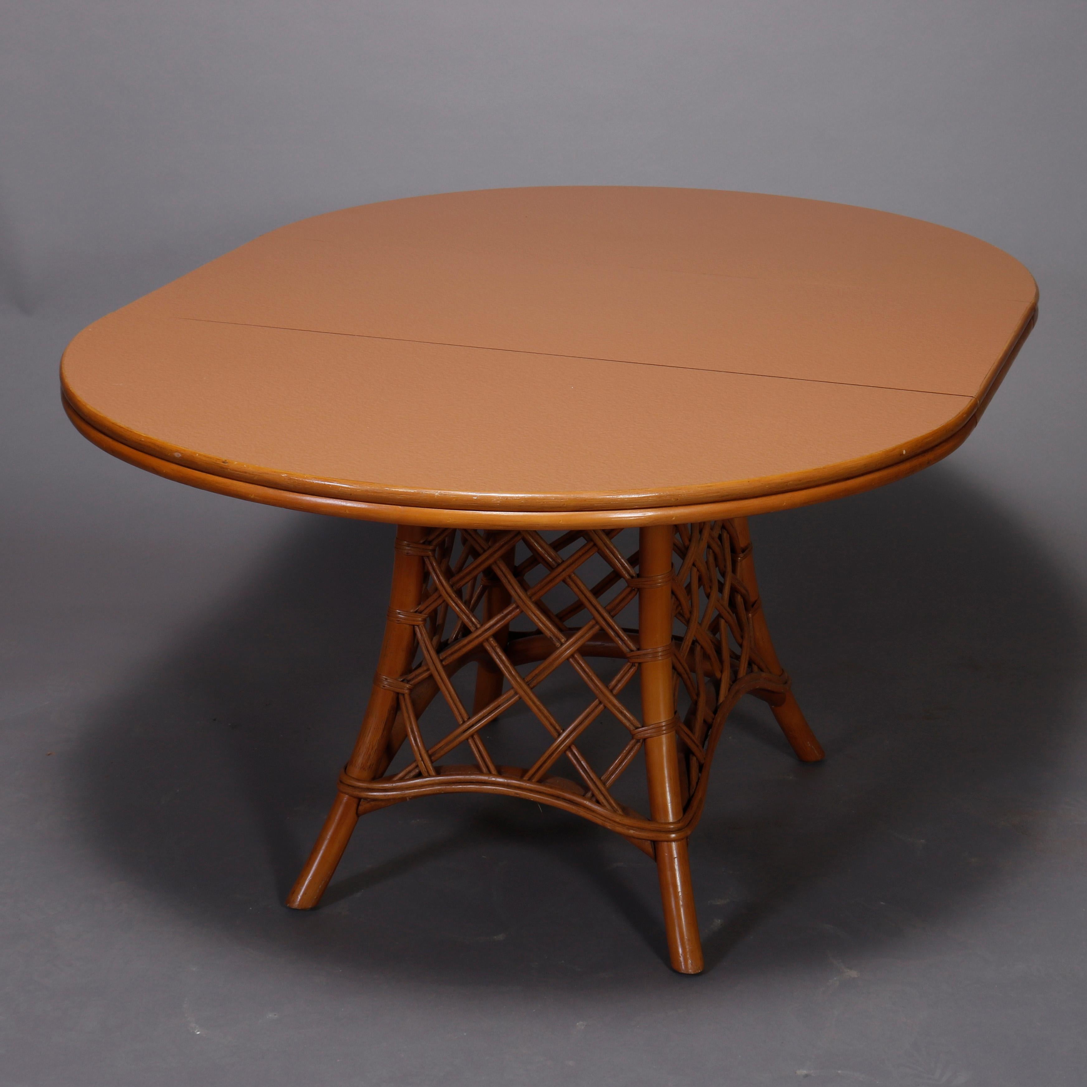 A Mid-Century Modern dining set offers rattan flared lattice pedestal base supporting laminate top having rattan bordering and single leaf, four swivel chairs have upholstered cushions, circa 1970

Measures: 60