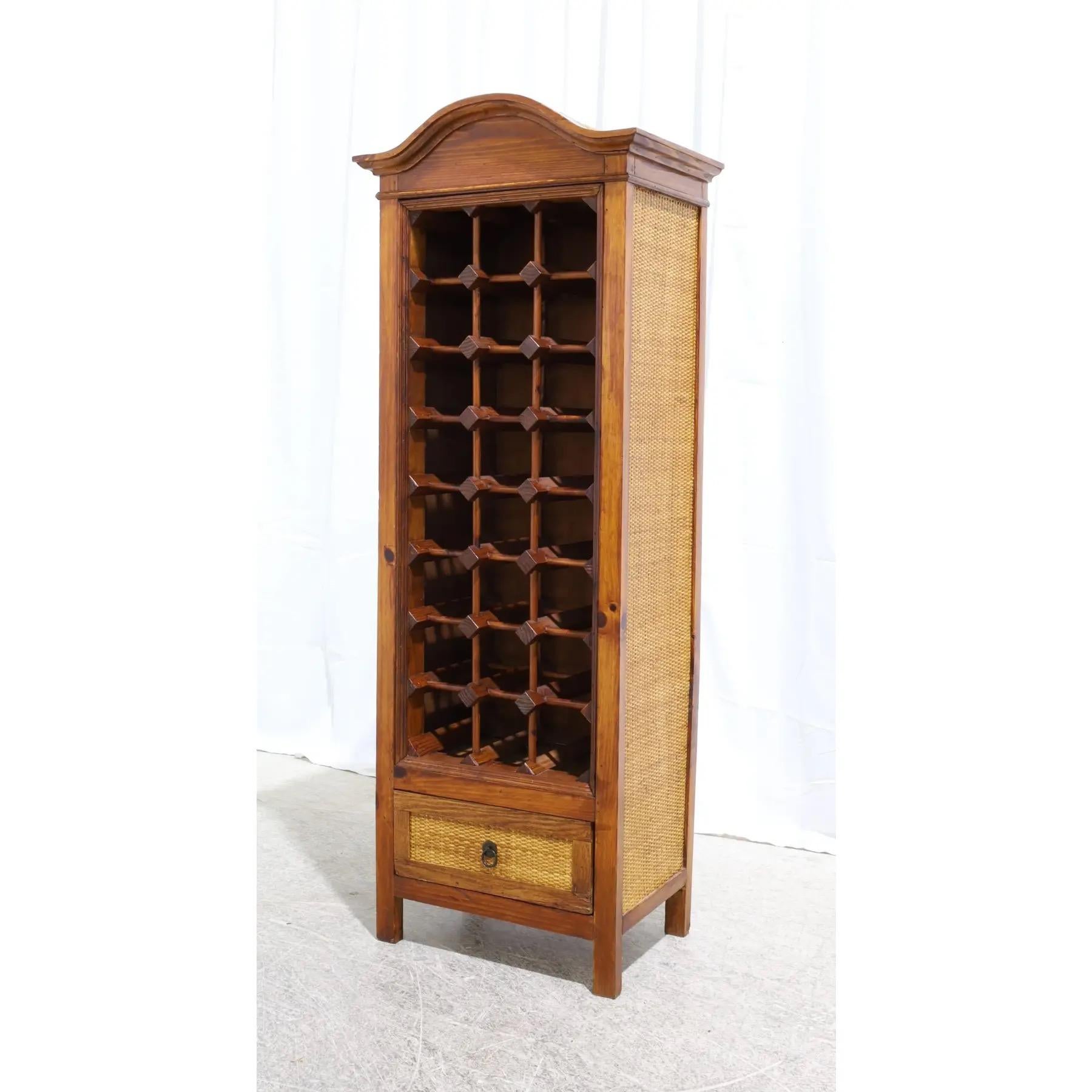 A rattan and wood wine rack; holds, 24 bottles of wine with storage drawer on bottom.