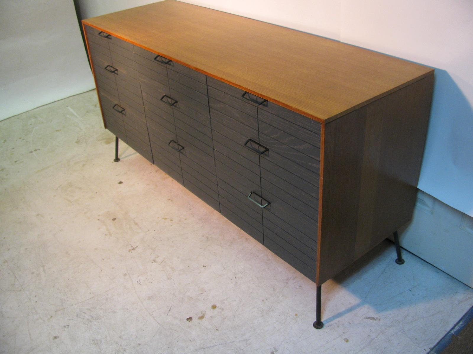 Simple and very elegant nine-drawer dresser constructed from Oak with iron legs and feet. Enameled drawer fronts in a striking contrast to the Oak case. Painted brass drawer pulls. Both have been restored.