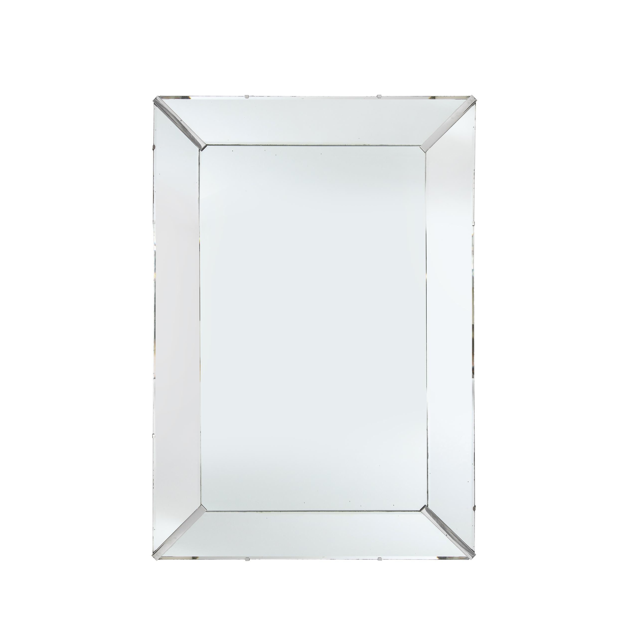This stunning Mid-Century Modern mirror was realized in the United States, circa 1950. It features a shadowbox form in a rectangular silhouette with beveled plain mirror segments secured in the corner with chrome inserts. With its austere form and
