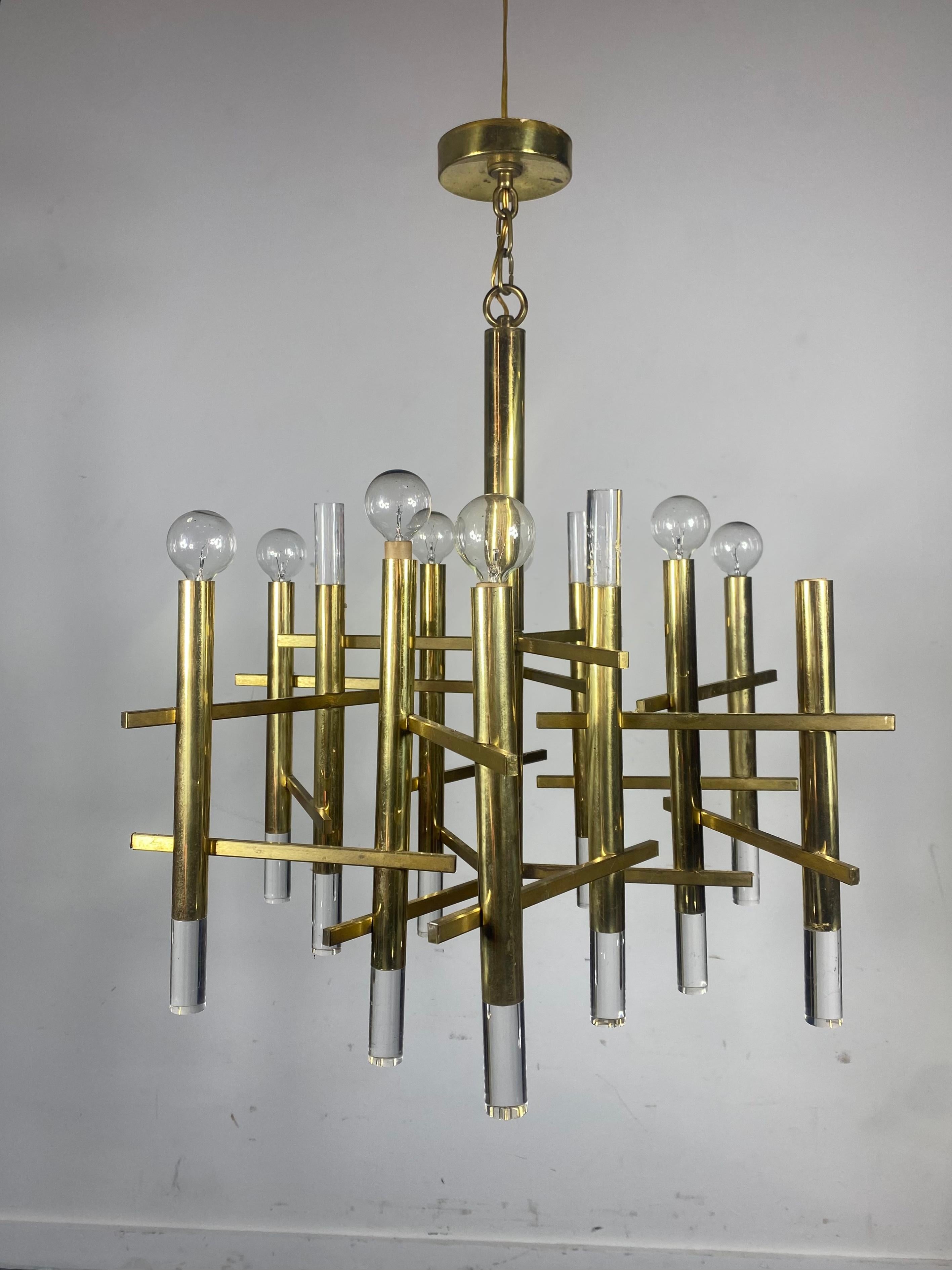 This refined rectilinear chandelier was realized by Gaetano Sciolari in Italy, circa 1970. It features a cylindrical body with six arms of the same form attached via rectangular slats to create a dynamic basket weave pattern in alternating segments