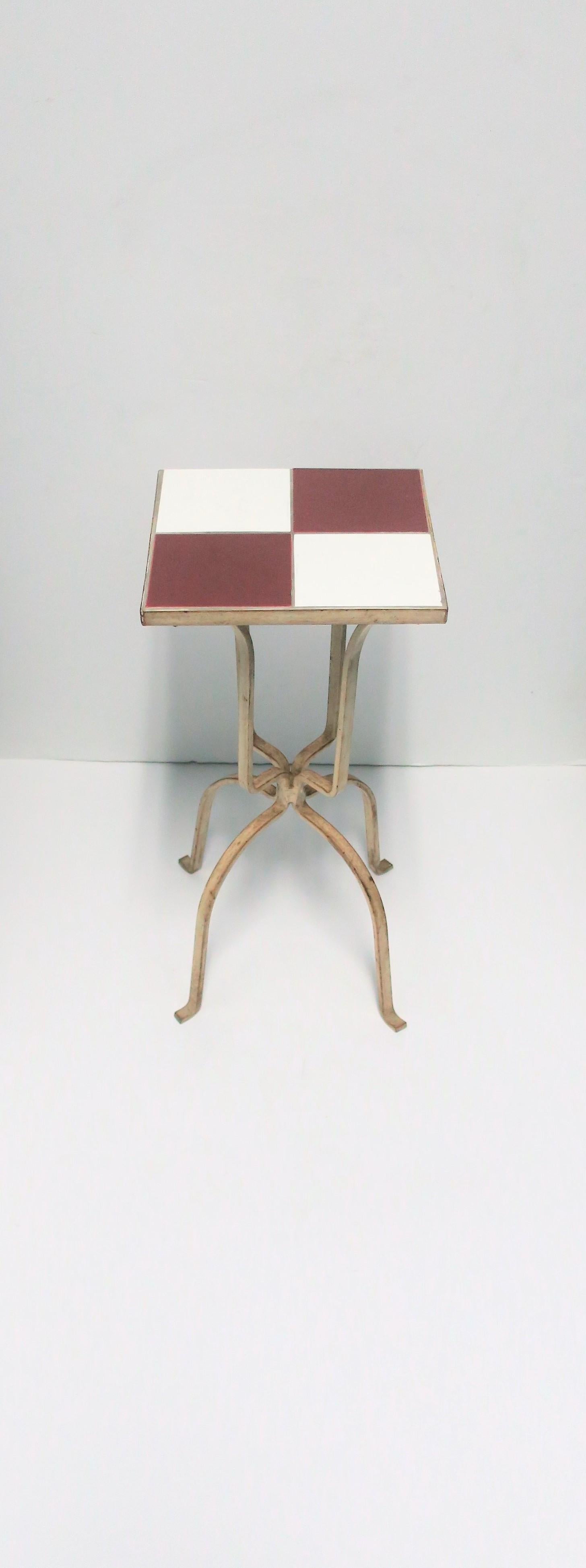 A small Mid-Century Modern square red and white ceramic mosaic tile top side or drinks table, circa mid-20th century. Table has a white metal frame with red/burgundy/'ox blood' and white/off-white ceramic tile top. Table is a convenient size
