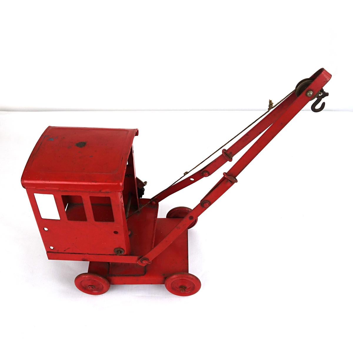 Steel toy crane with lots of appeal. It is plain and pretty, sitting on four wheels. The hook really works well.