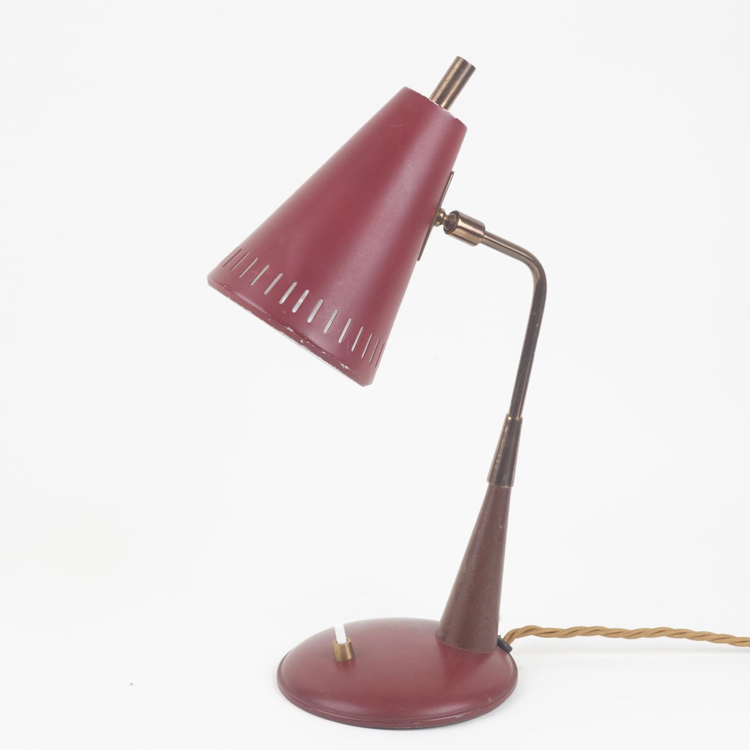 Articulated Mid-Century Modern desk lamp in dark red metal on Teak wood and brass arm is Modernist in design.
