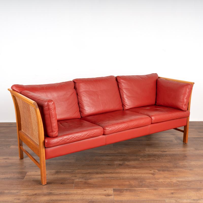This attractive three-person sofa is by Okamura & Maquardsen for Skipper Furniture, the 'Ambassador' model. The striking red leather with loose cushions in back and seats is in very good vintage condition (minor scuff mark on right seat cushion), as