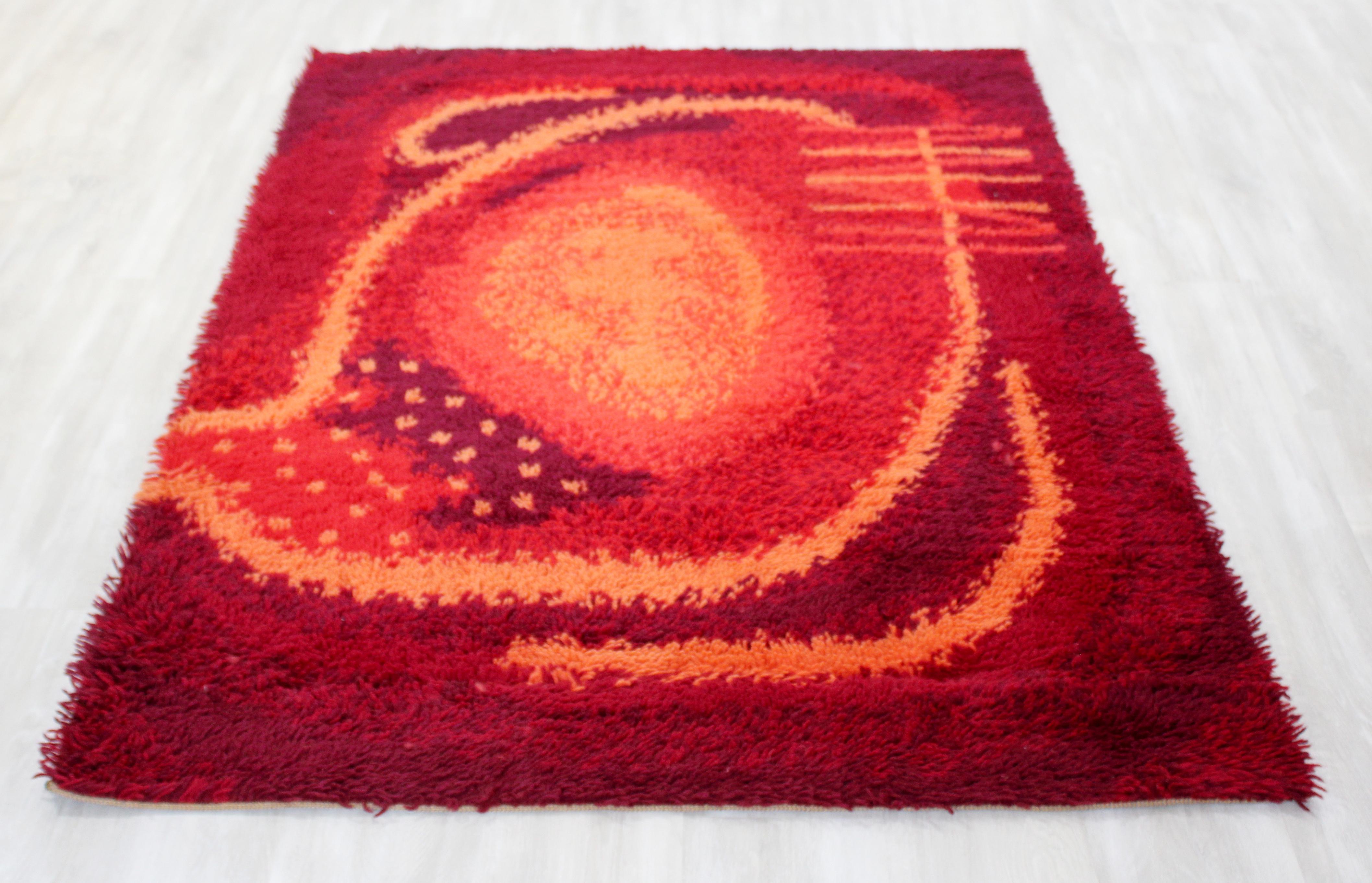 For your consideration is a vibrant, Danish, rectangular Rya area rug or carpet, with a red and orange pattern, circa the 1960s. In very good condition. The dimensions are 72