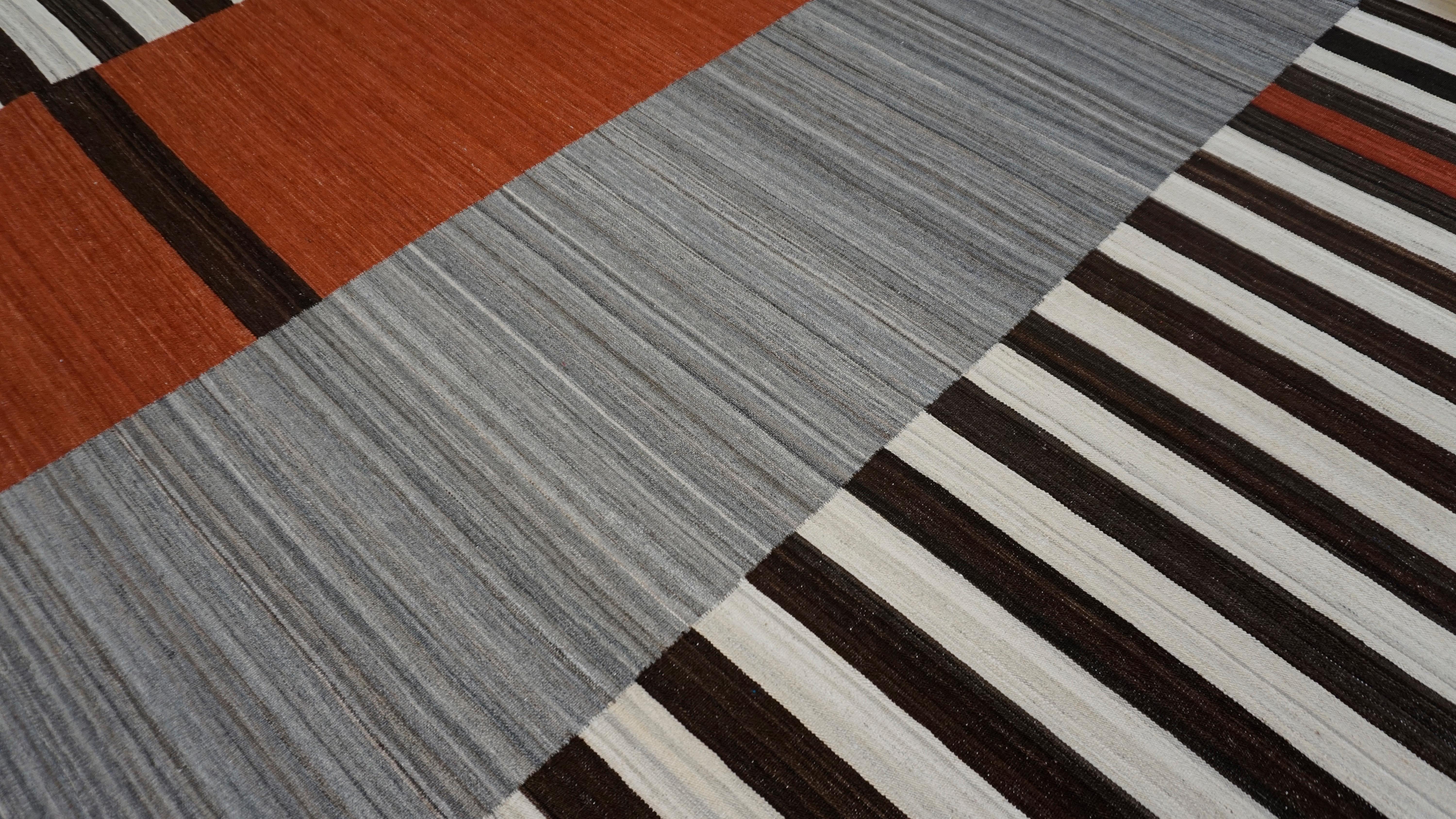 This striking handwoven wool kilim is a bold fusion of geometric abstraction and traditional textile technique. Inspired by Bauhaus and mid-century modern aesthetics, the rug features a powerful composition of horizontal stripes, color-blocked