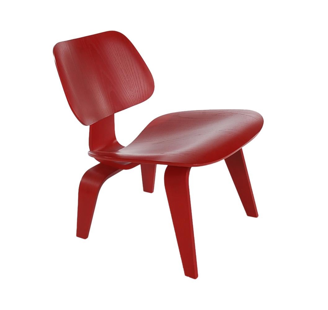 A handsome matching pair of red dyed plywood lounge (LCW) chairs designed by Charles Eames and produced by Herman Miller. These features bent plywood construction with red dye finish that shows the beautiful wood grain.