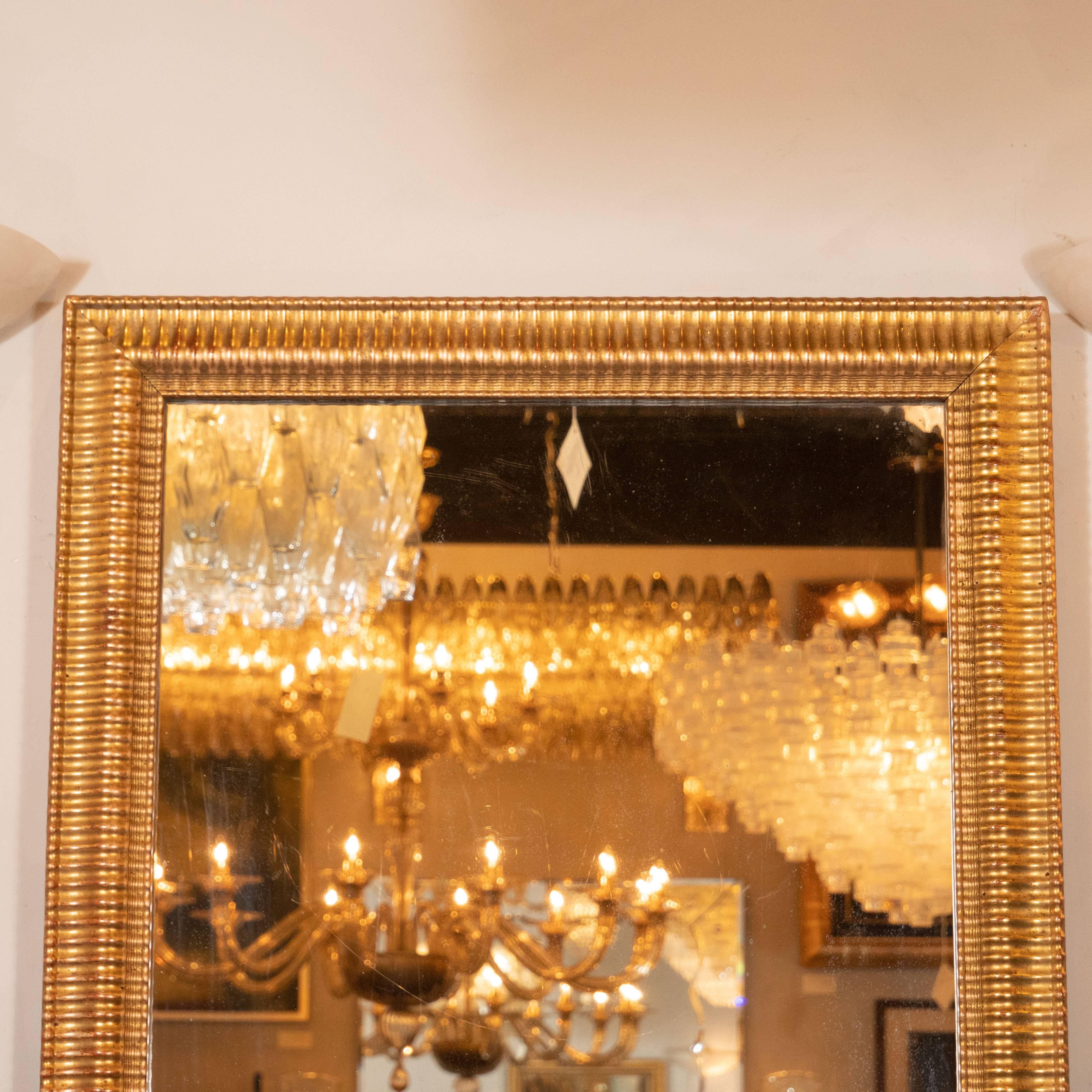 This refined and elegant mirror was realized in the United States, circa 1950. It features a rectangular frame, meticulously hand embellished with horizontal fluted detailing and undulating fronts, lending the frame a subtle sculptural sensibility.