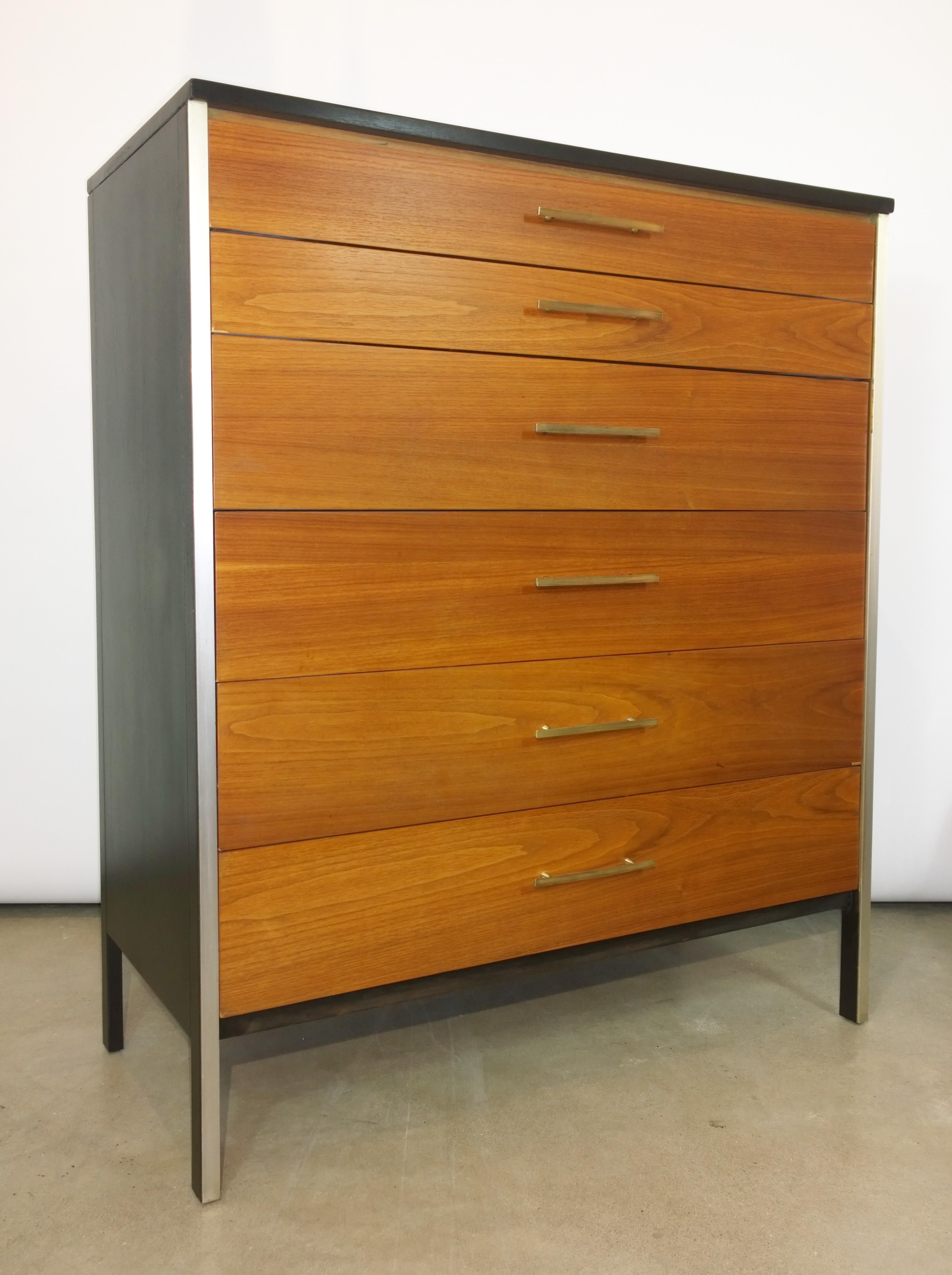 Offered is a signed Mid-Century Modern Paul McCobb for Calvin refurbished black walnut frame with six natural color walnut drawers, accompanied by brass pulls and accents, chest of drawers / highboy. The frame of the dresser has been recently