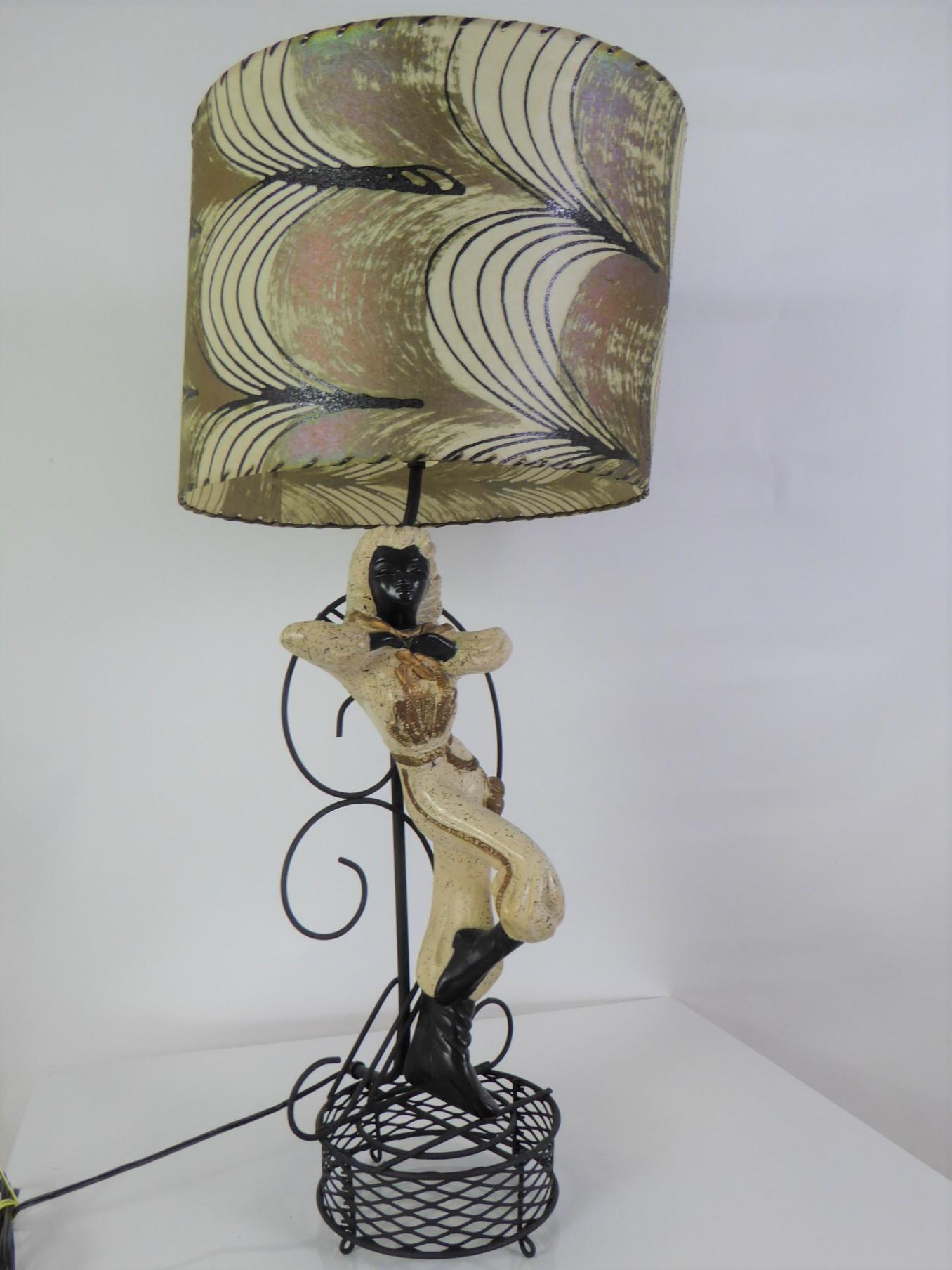 Diese schöne Gipslampe aus der Mitte des Jahrhunderts zeigt ein argentinisches Gaucho-Mädchen mit ihrem Kopftuch um den Hals und ihren Bolos (Waffen) an der Seite. Farbpalette Schwarz, Creme mit goldenen Akzenten.
Die Lampe wurde neu verkabelt und