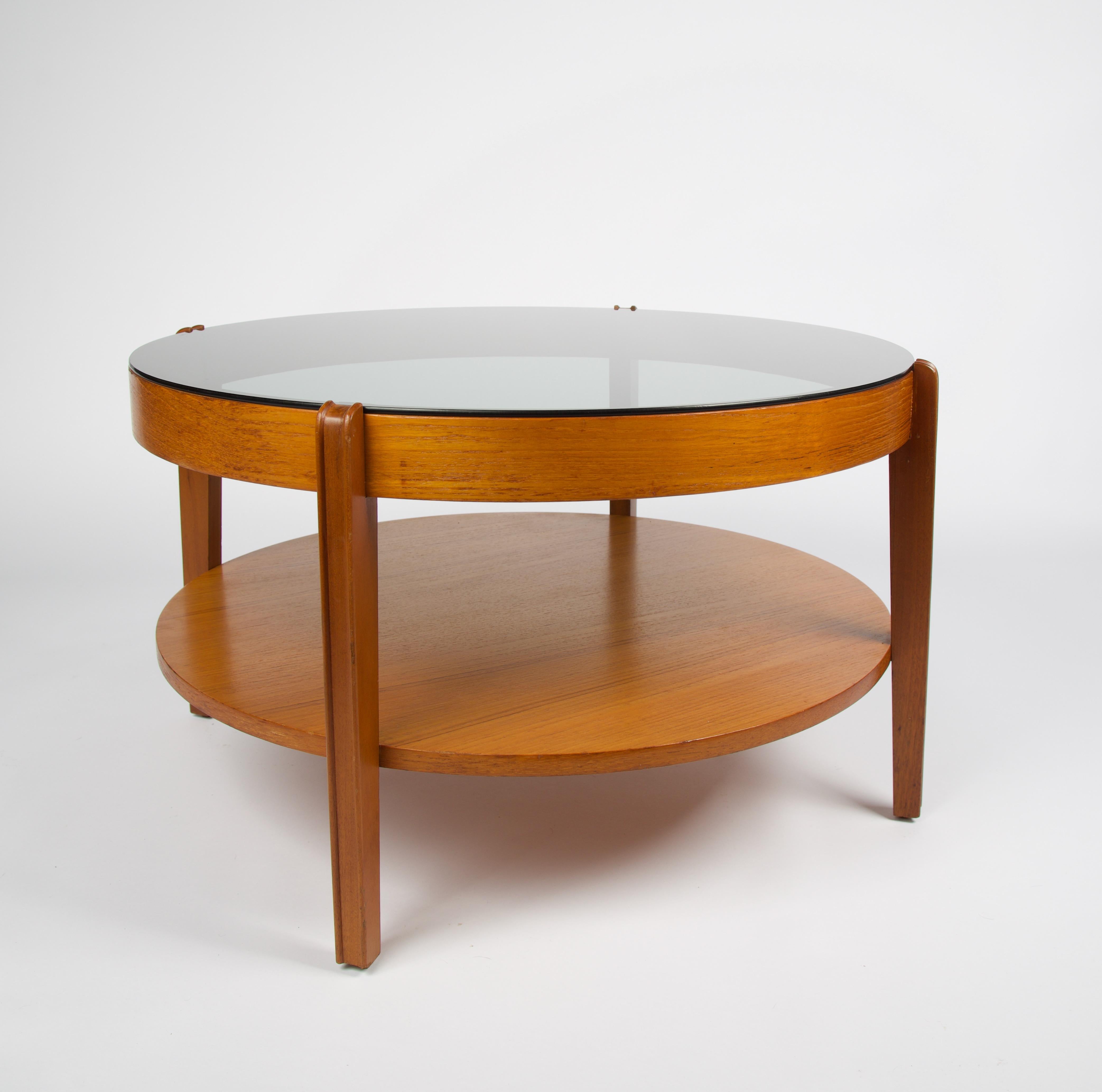 Mid-Century Modern round teak coffee table with smoked glass by Remploy of England.

Remploy was set up under the 1944 Disabled Persons Employment Act by Ernest Bevin, who was then minister of labour; to become yet another plank in Welfare State