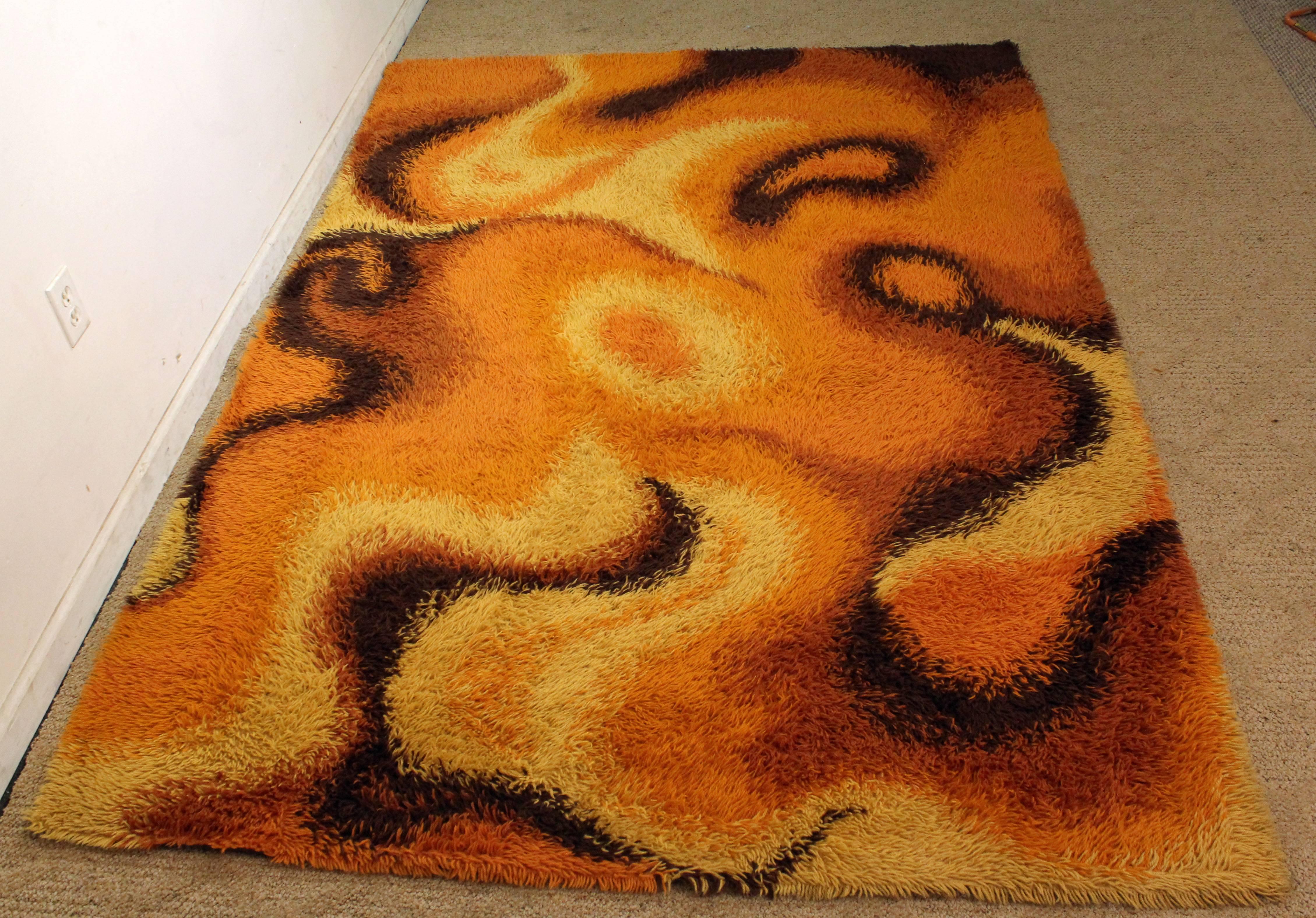 Offered is a midcentury orange shag rug with a groovy design. In good condition, shows some age wear. It is not signed.
