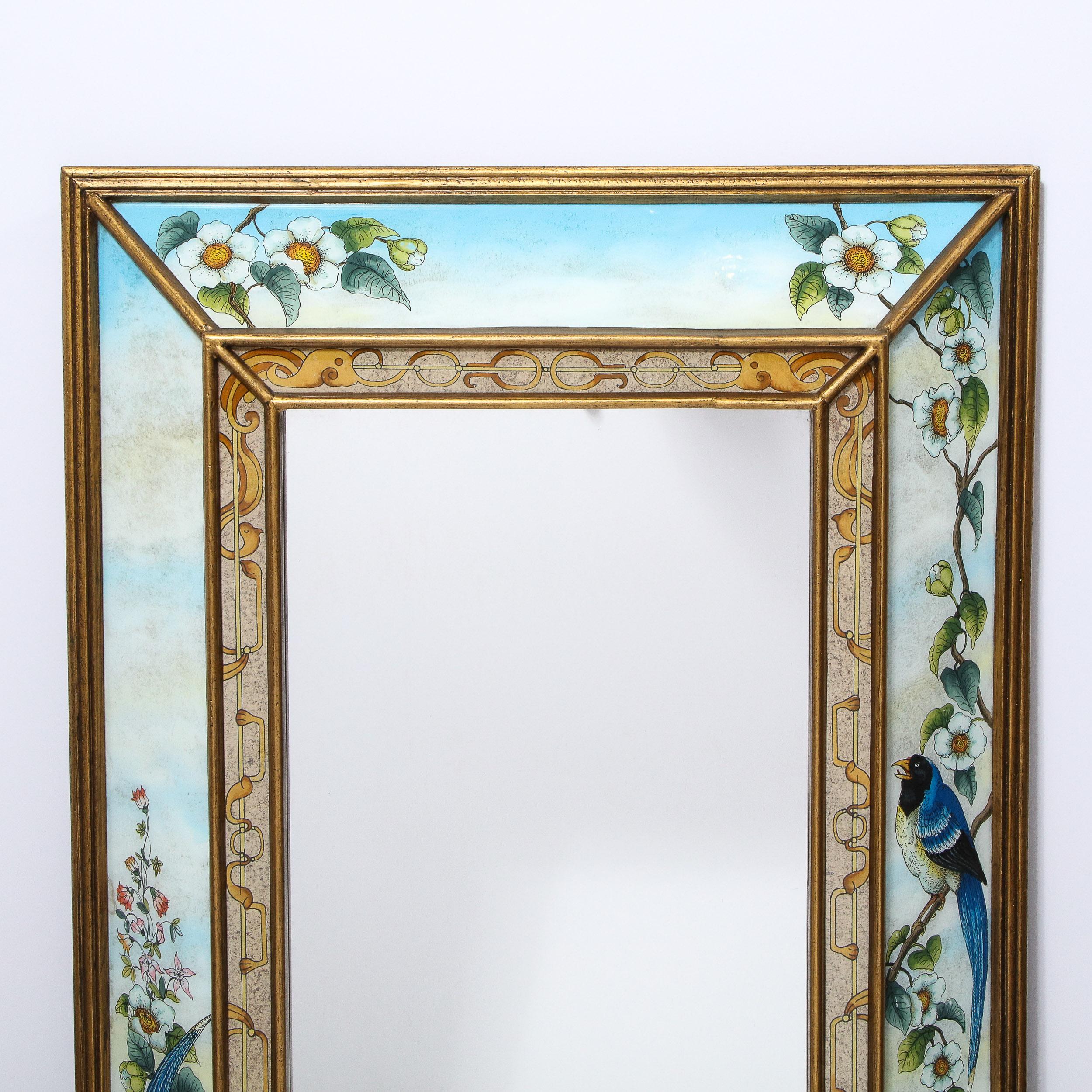 This whimsical and sophisticated Mid-Century Modern mirror was realized in the United States circa 1950. It features a giltwood border with reverse eglomise painted panels depicting a variety of stylized flora and fauna- including apple blossoms and