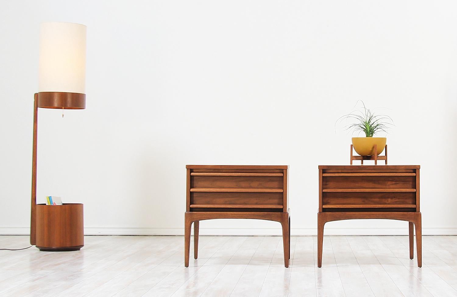 Pair of Mid-Century Modern nightstands designed and manufactured in the United States by Lane Furniture circa 1950s. This beautiful set of night stands feature a sturdy walnut wood case with a sleek and minimal design ideal for modern interiors.