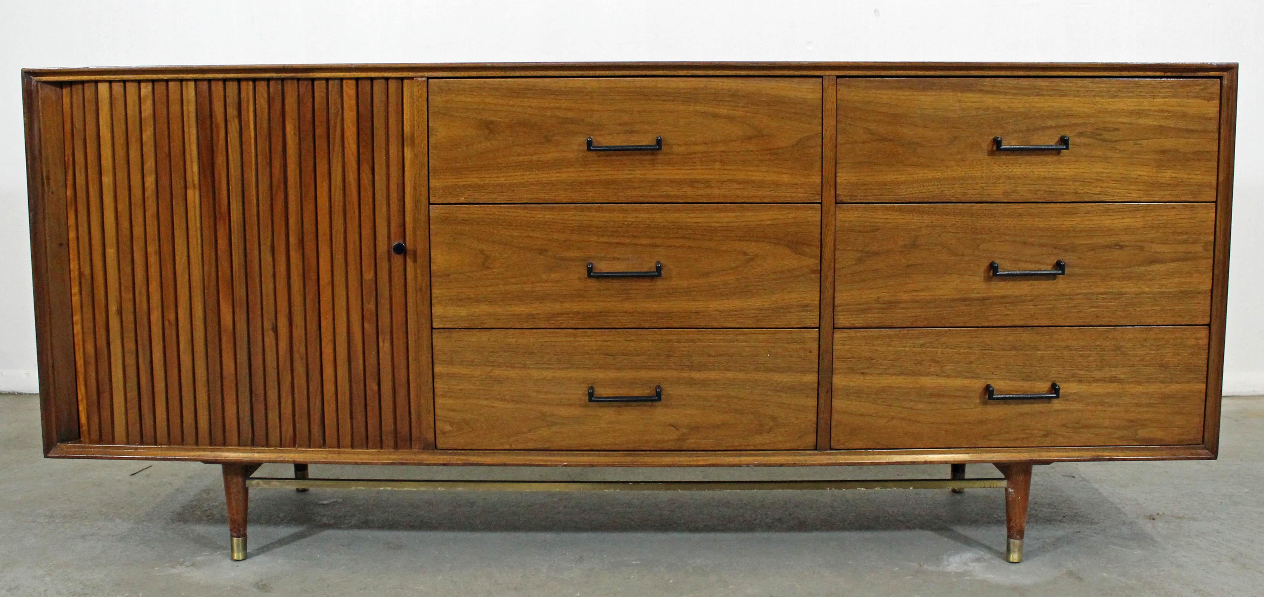 Nous vous proposons un parfait exemple de mobilier américain du milieu du siècle dernier : une crédence à porte tambour en noyer et laiton, conçue par Mark J. Furst et Robert Fellner pour Furnette. Il comporte une porte tambour à droite et 9 tiroirs