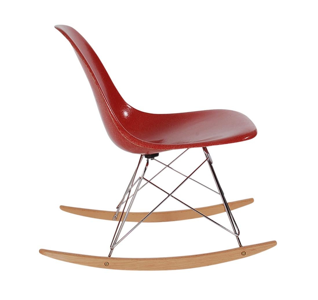 A beautiful and uncommon red fiberglass rocking chair designed by Charles Eames for Herman Miller. It features a vintage fiberglass shell chair on a newer production rocker base. Embossed manufacture logo on bottom of chair.
