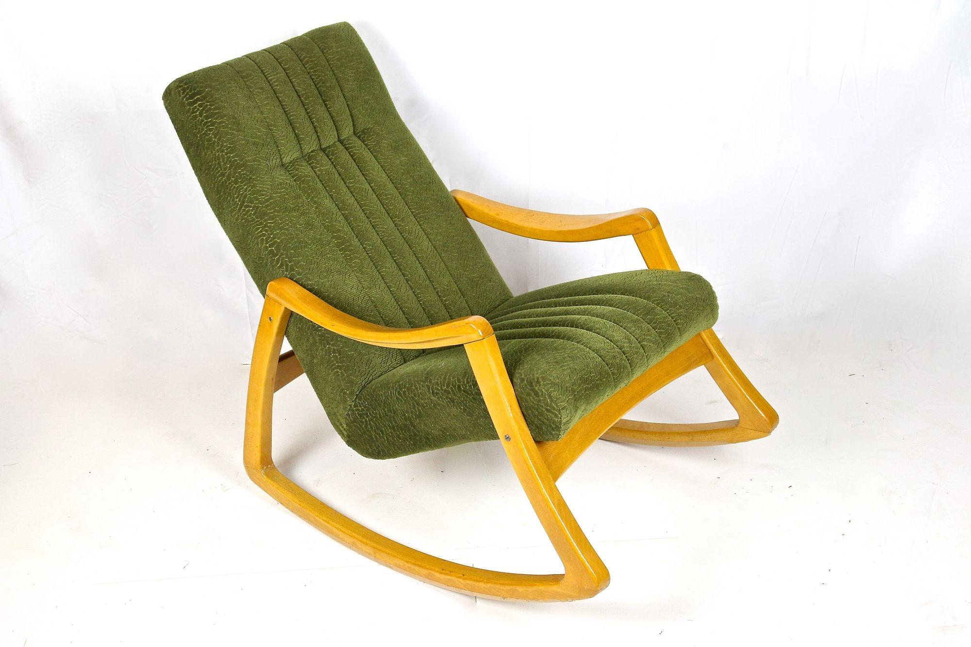 Stylish designed Mid-Century Modern rocking chair made by the czech company of TON around 1953. This unusual rocking chair impresses with a very uncommon design made of Fine laquered beech. The great looking, still original moss green fabric builds