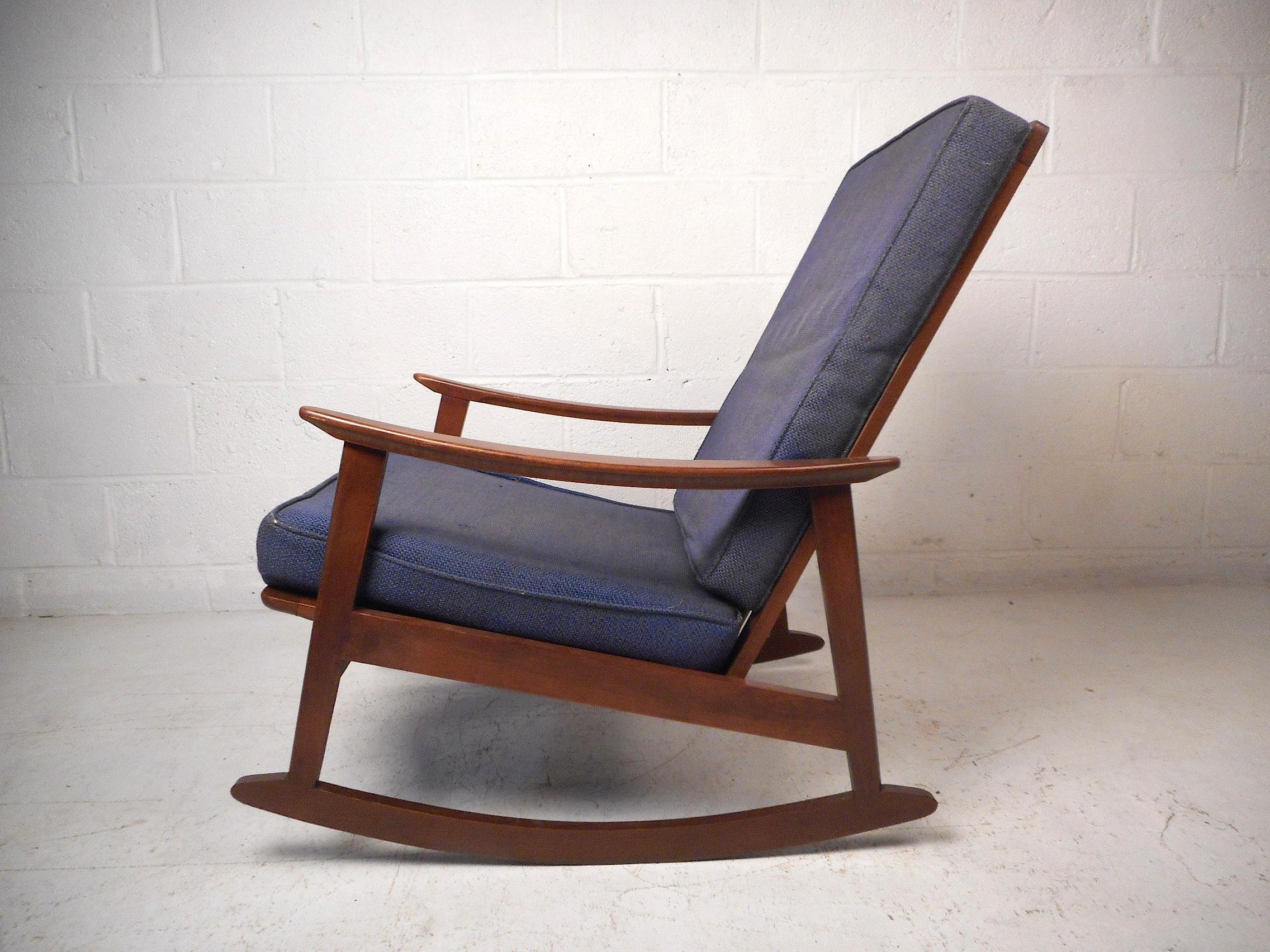 Dieser beeindruckende moderne Schaukelstuhl im Vintage-Stil zeichnet sich durch eine robuste Konstruktion aus Nussbaumholz, geschmeidig geformte Armlehnen und eine hohe Rückenlehne aus, die sowohl Komfort als auch Stil gewährleisten. Eine großartige