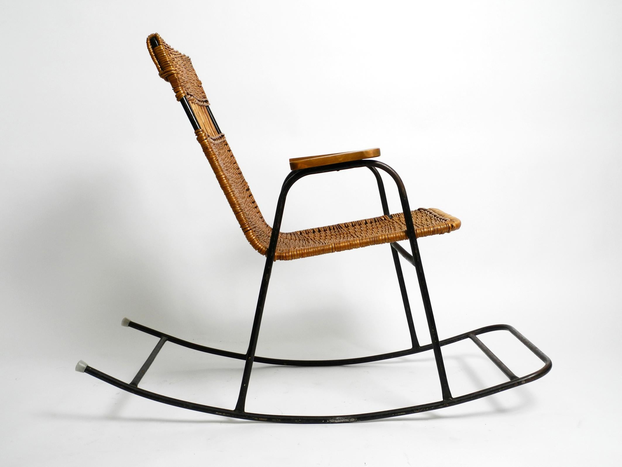 Beautiful Mid-Century Modern rocking chair with armrests made of black painted metal and rattan.
Typical 1950s design. Stunning beautiful piece.
Frame is entirely made of black lacquered iron. Seat with backrest are made of rattan weave.
Solid