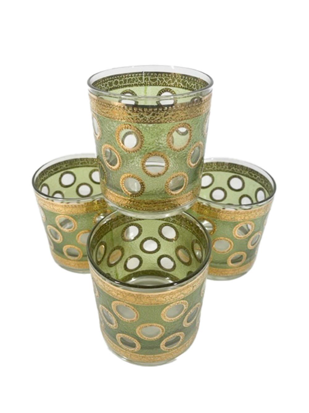 Four Mid-Century Modern rocks glasses attributed to Culver, LTD with a textured translucent green enamel having three rows of clear circles with raised textured 22k gold edges, the green ground is also bordered top and bottom with a gold band.