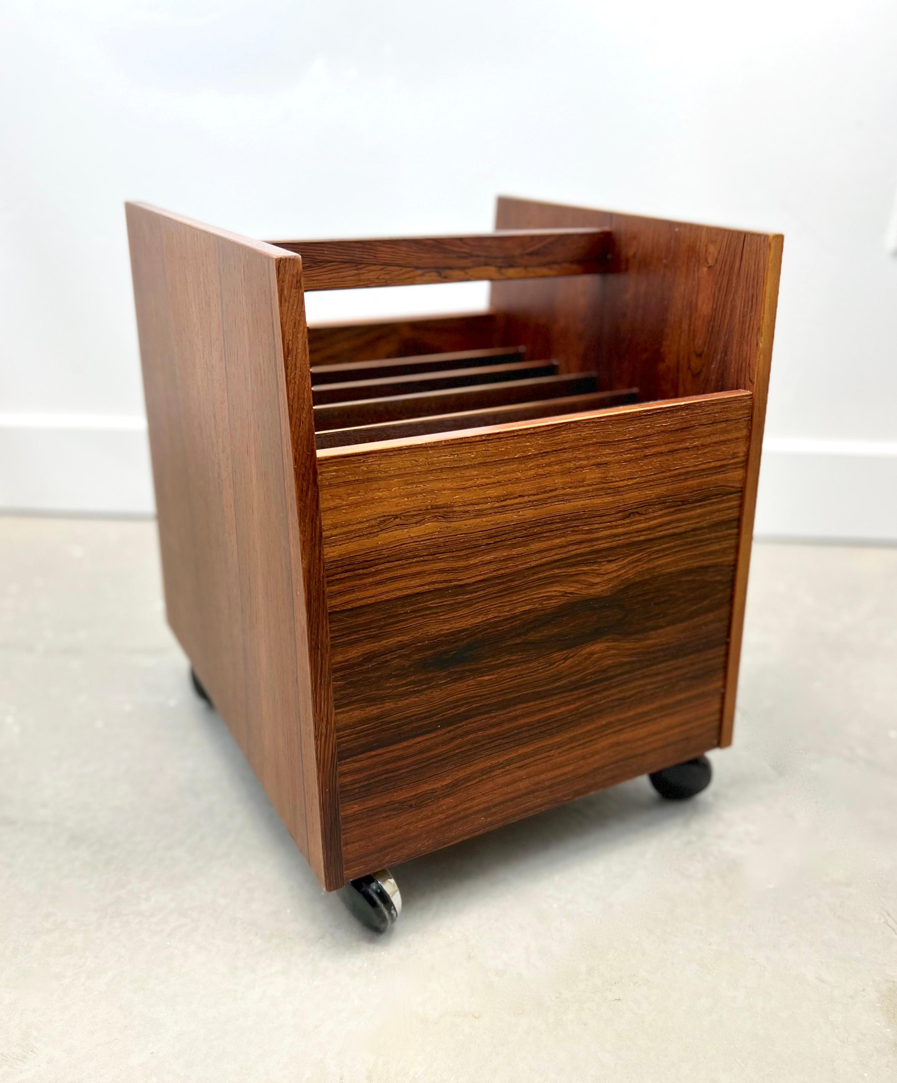 Stunning Mid-Century Modern Rolf Hesland rosewood magazine/record rack by Bruksbo of Norway. This rolling rack is in excellent condition with beautiful rosewood grain and six compartments for magazines or records. It has had very light use and the