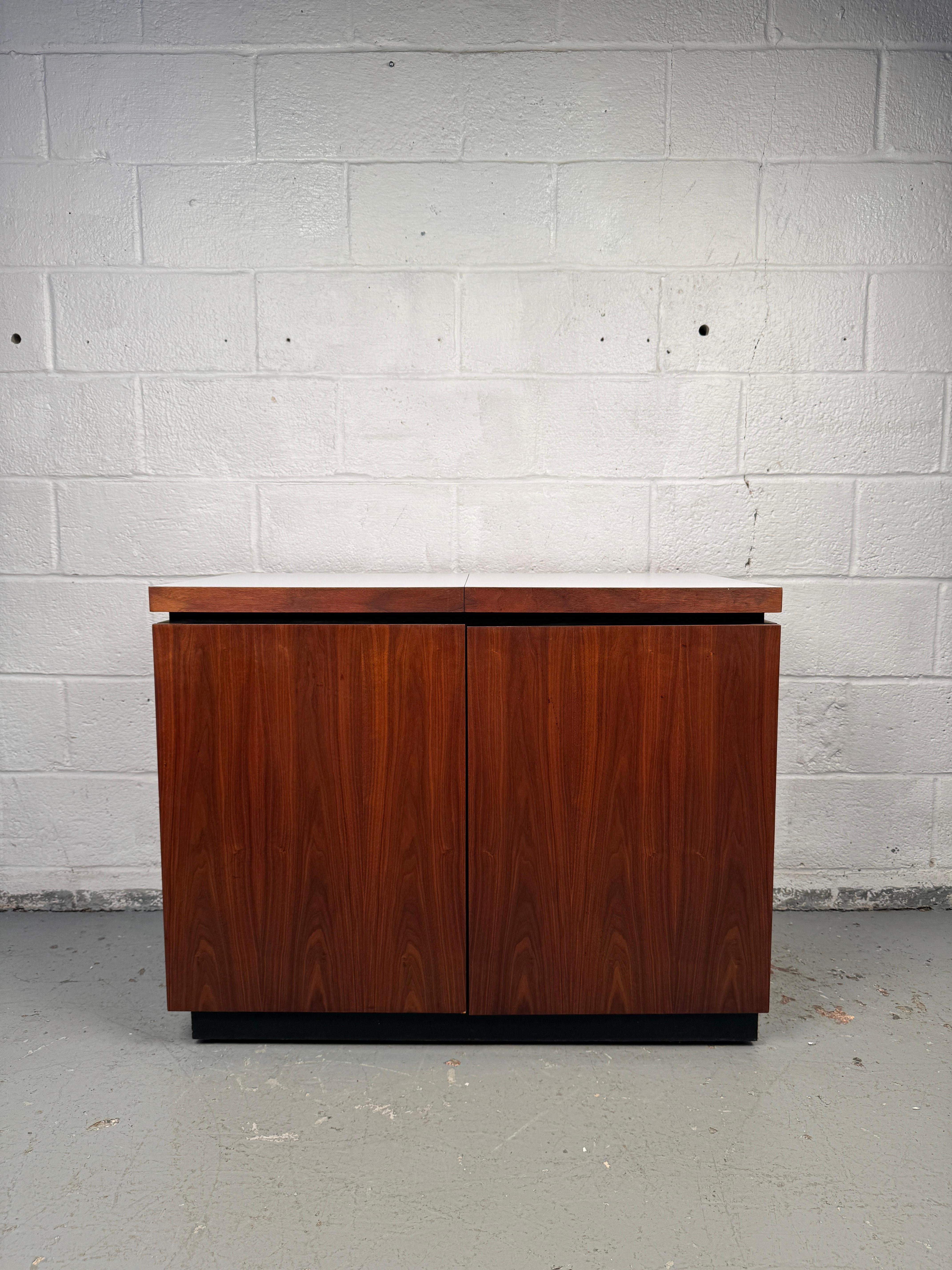 A sophisticated mid-century rolling bar, featuring a sliding top that opens to reveal a fitted ice compartment. Ample storage for wine bottles, glasses, and silverware. Designed with clean lines, warm grain, and smooth-rolling casters, this